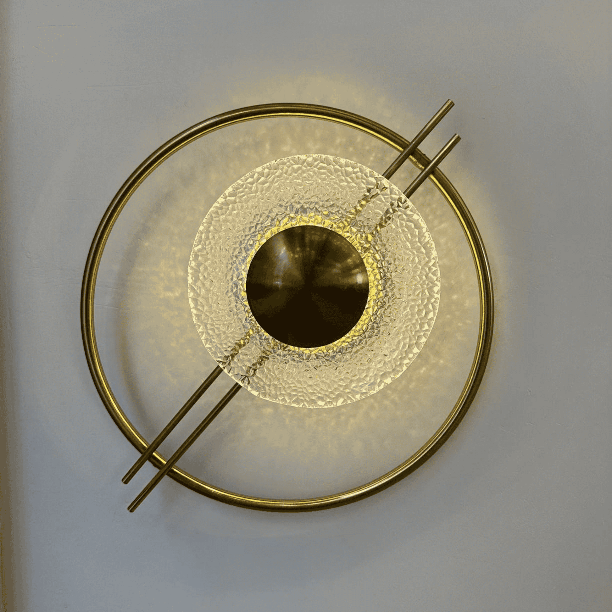 Brass and textured glass wall light emitting warm light, perfect for stairway use in Art Deco or Mid-Century settings.