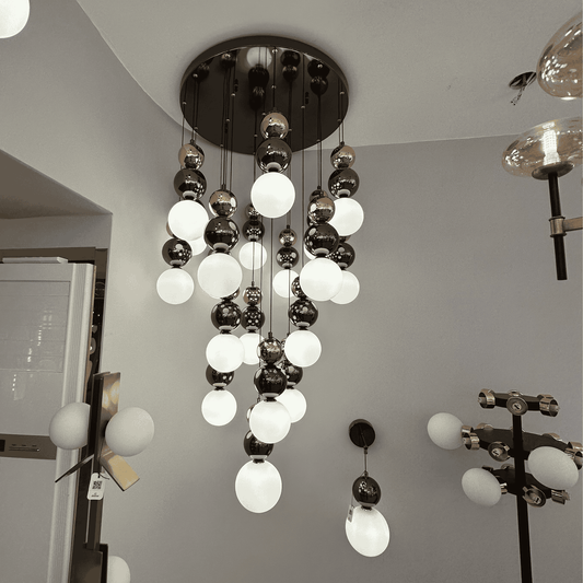 A tiered pendant lighting fixture with black and white glass globes, designed for modern interior applications.