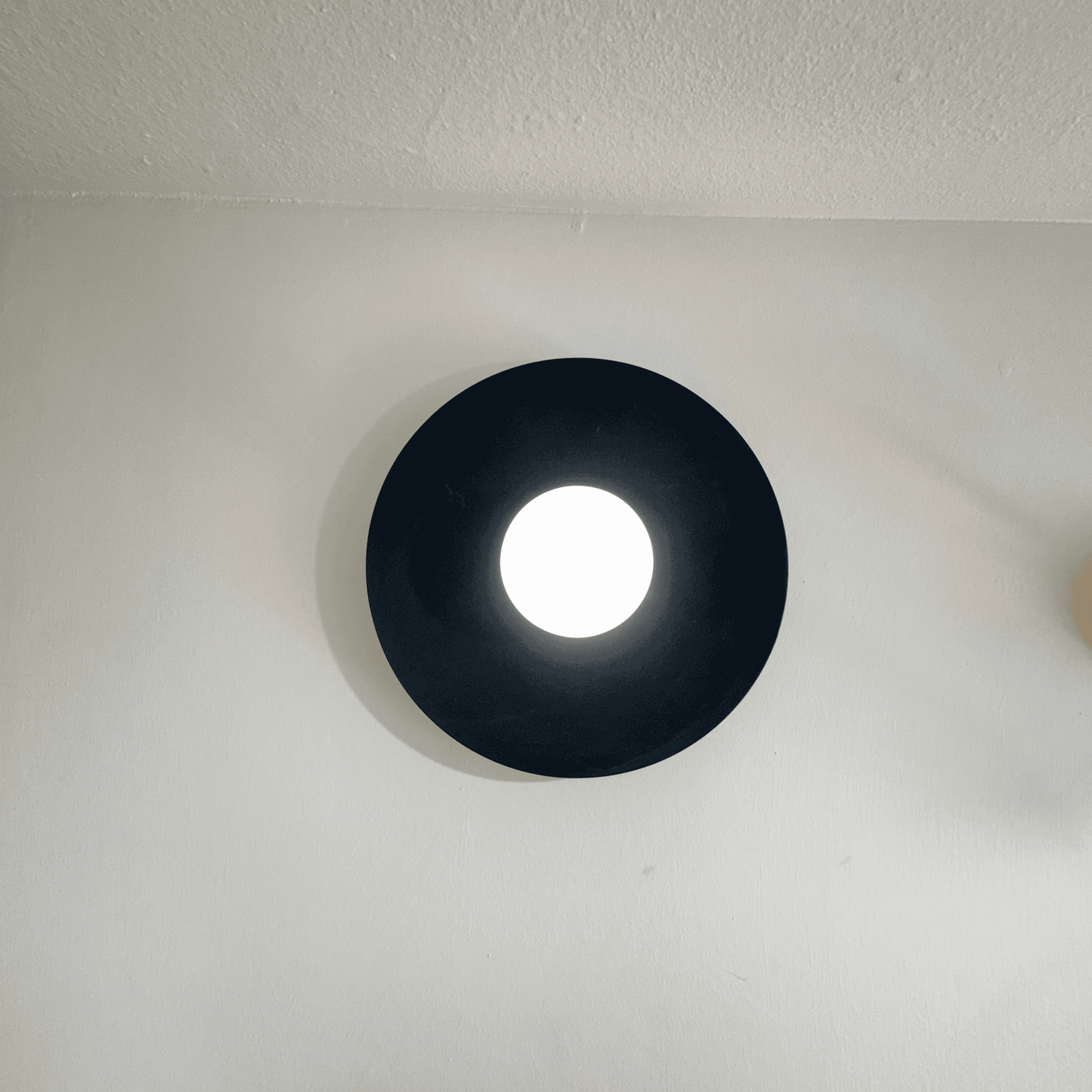 Black circular light fixture on a white ceiling