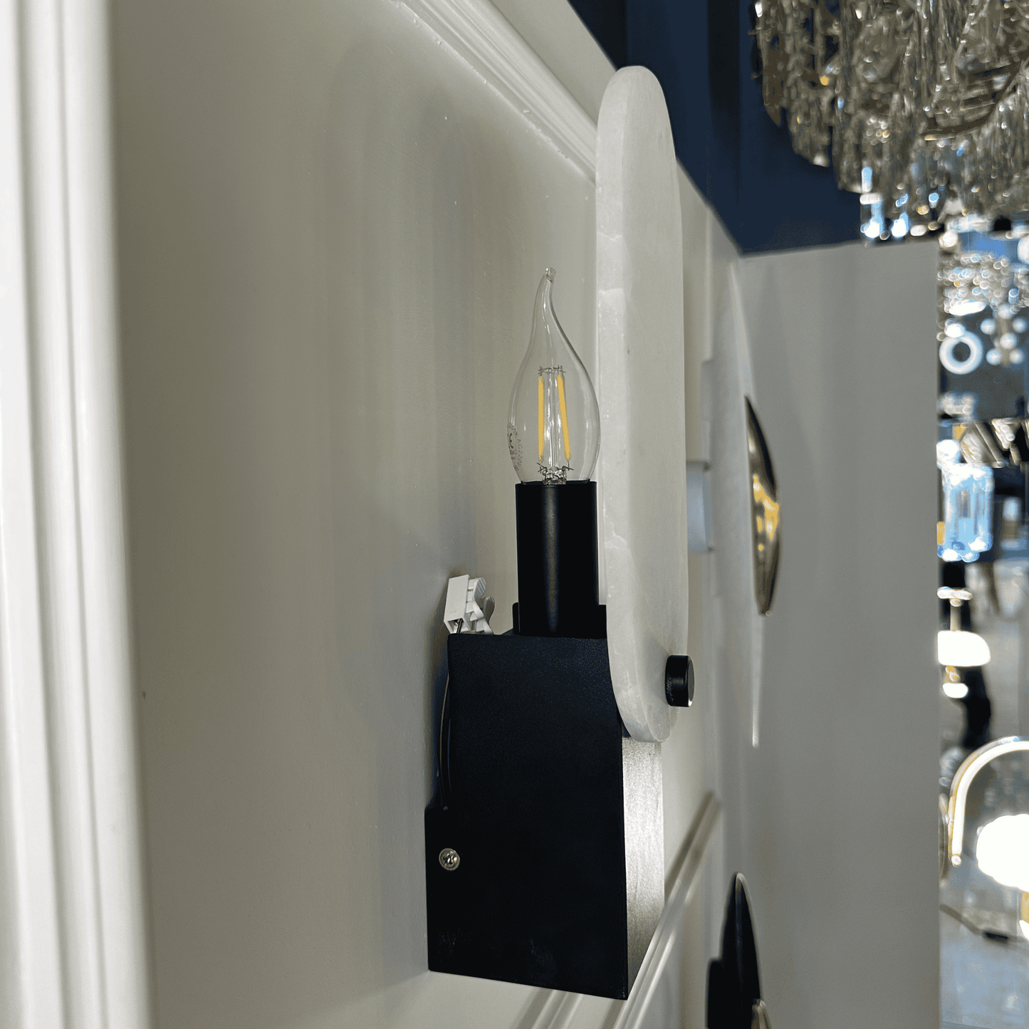 Side profile of matte black marble wall sconce with exposed LED bulb and white stone shade.