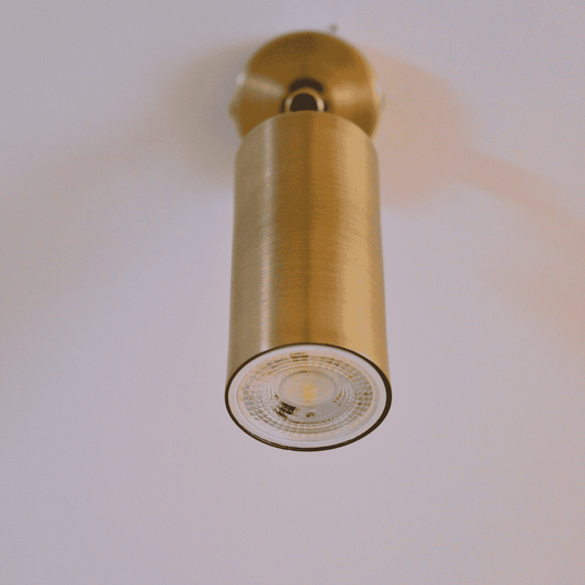 Close-up of brass cylinder directional light with pivot mount for modern lighting.