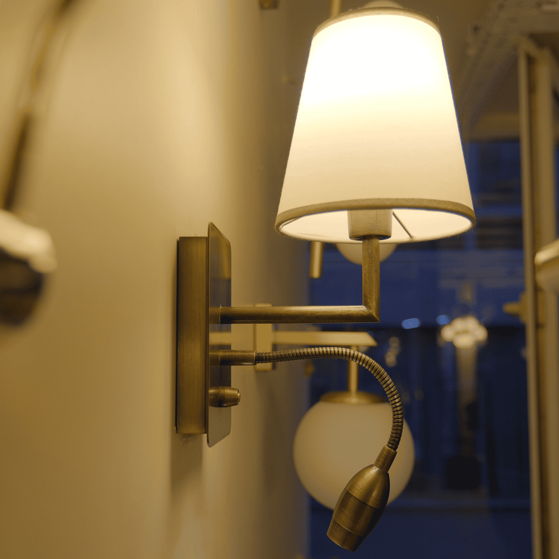 Dual-light brass wall sconce with modern shade and flexible LED arm.