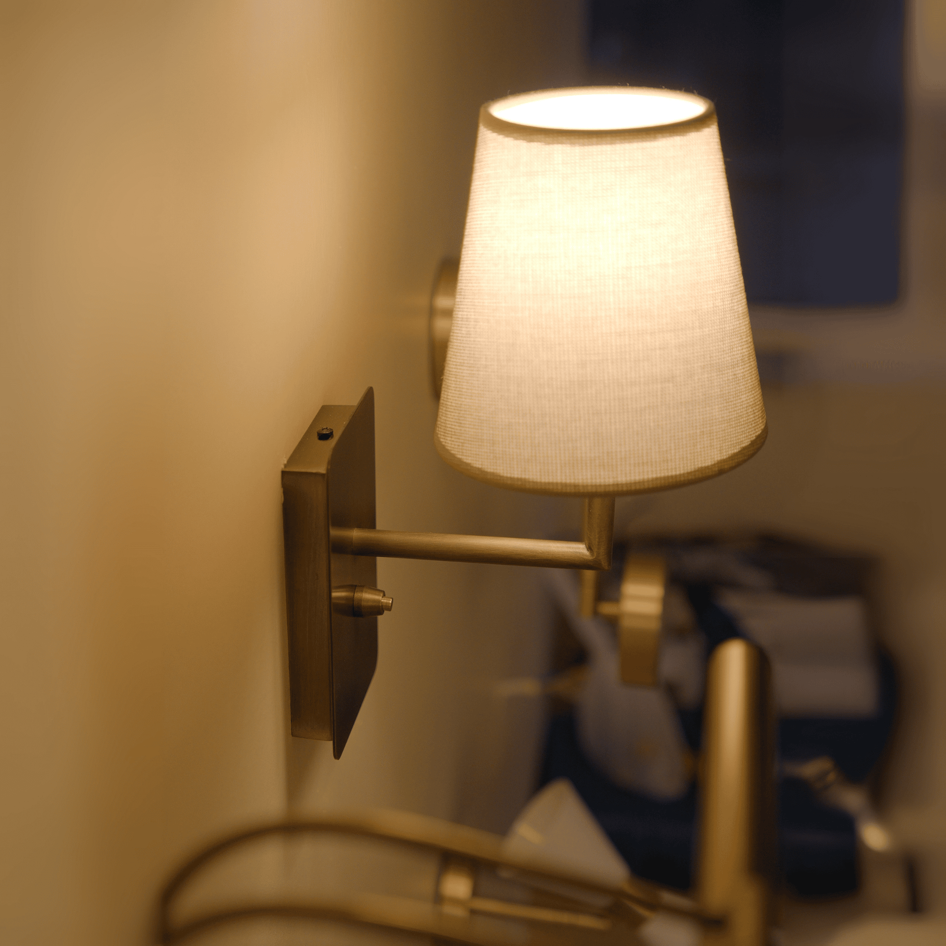 Brass wall light with fabric shade providing warm ambient lighting for modern interiors.