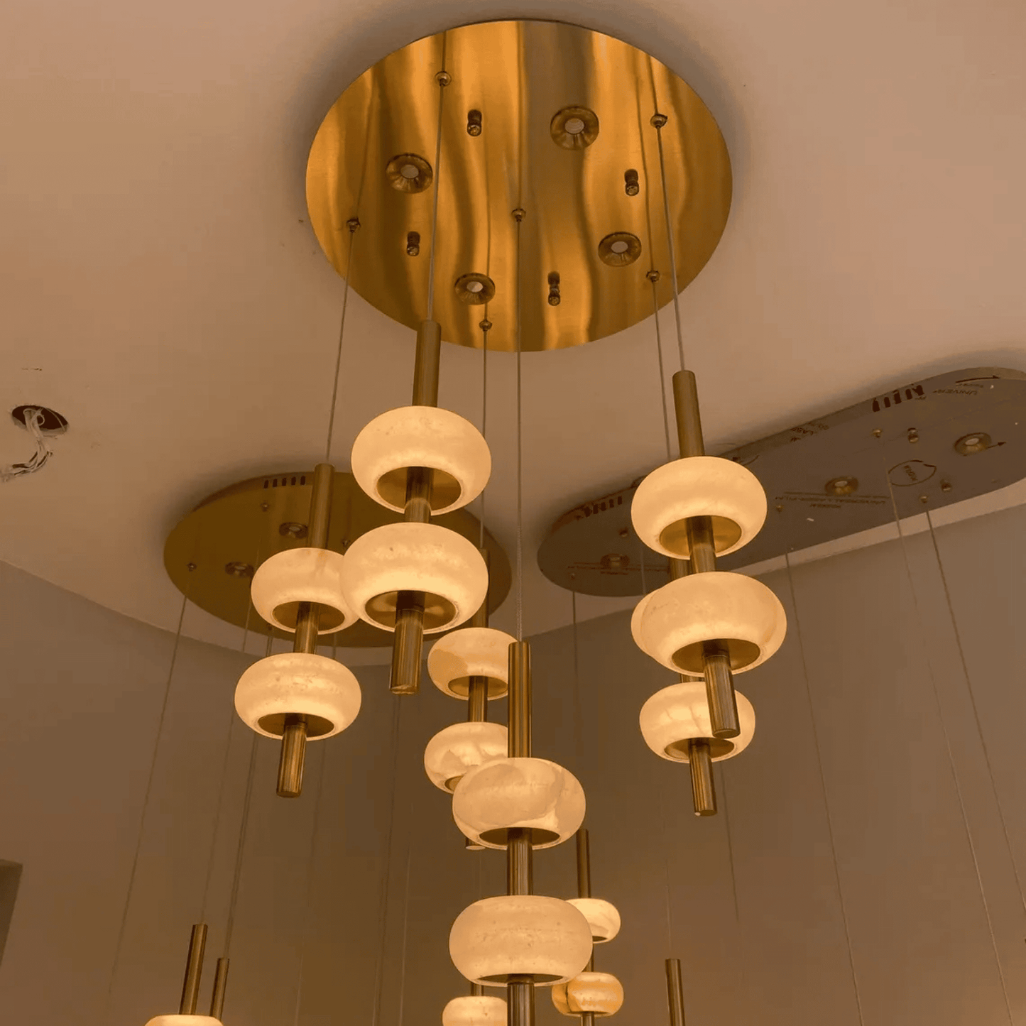 Ceiling-mounted alabaster pendant light array with brass finishes and soft glow.