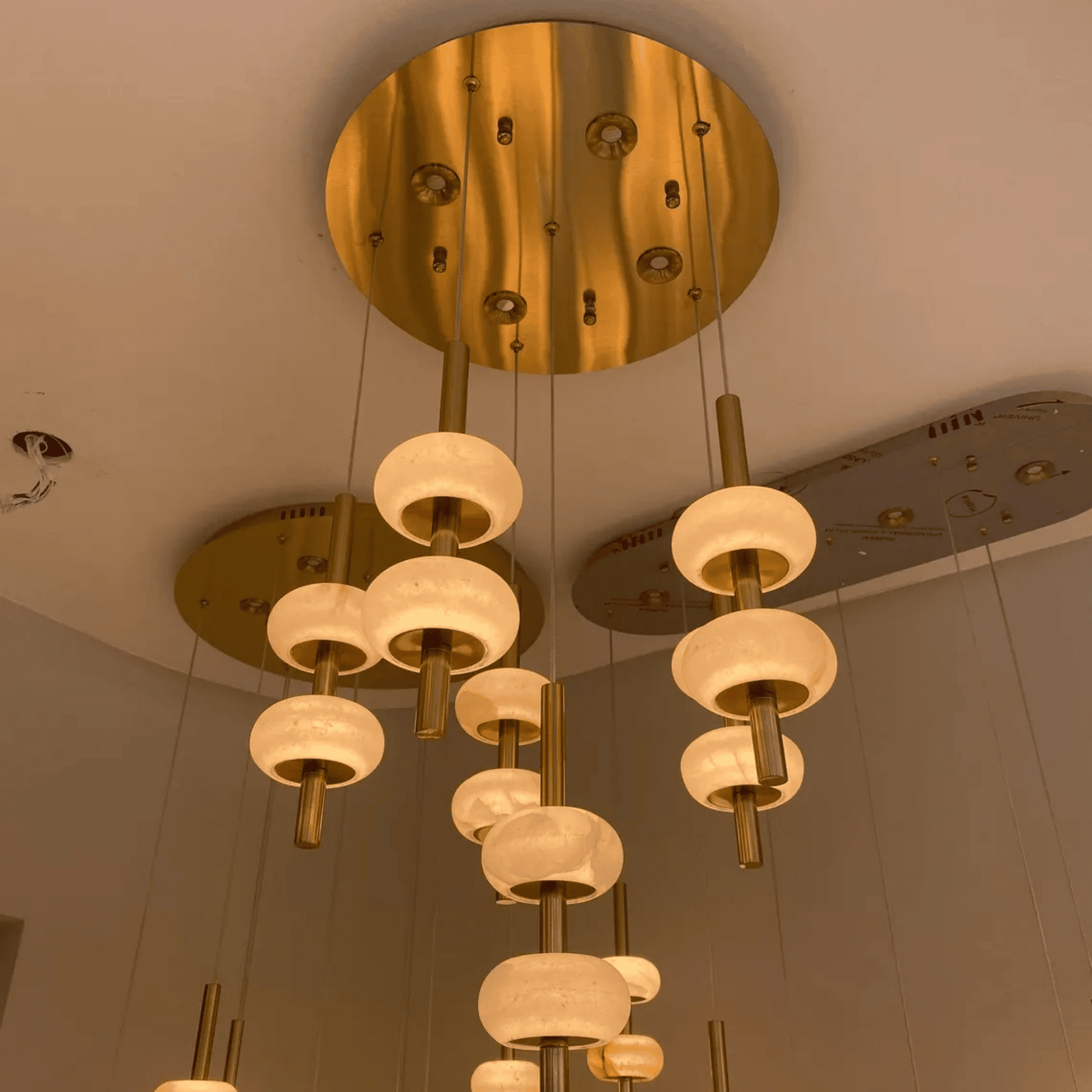 Ceiling-mounted alabaster pendant light array with brass finishes and soft glow.
