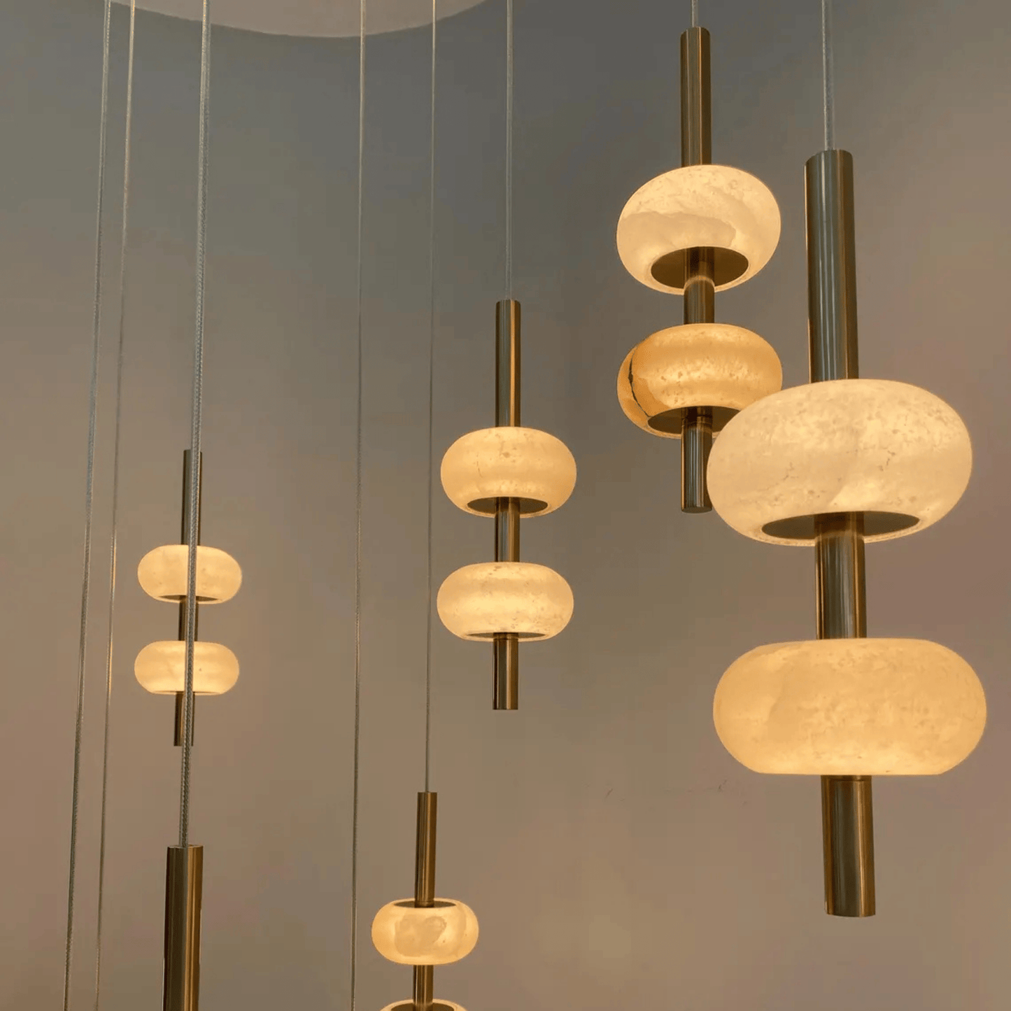Multiple alabaster pendant lights with brass hardware hanging in a modern space.
