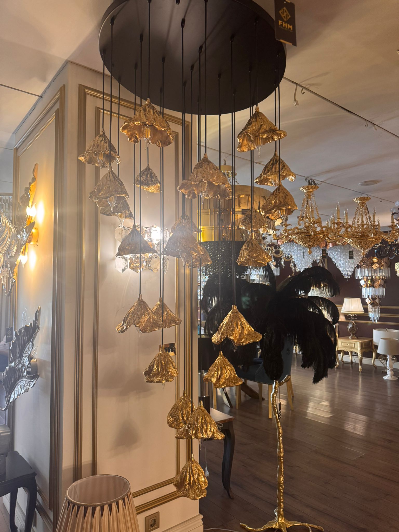 Illuminated cluster of pure brass leaf pendant lights in a luxury showroom setting.