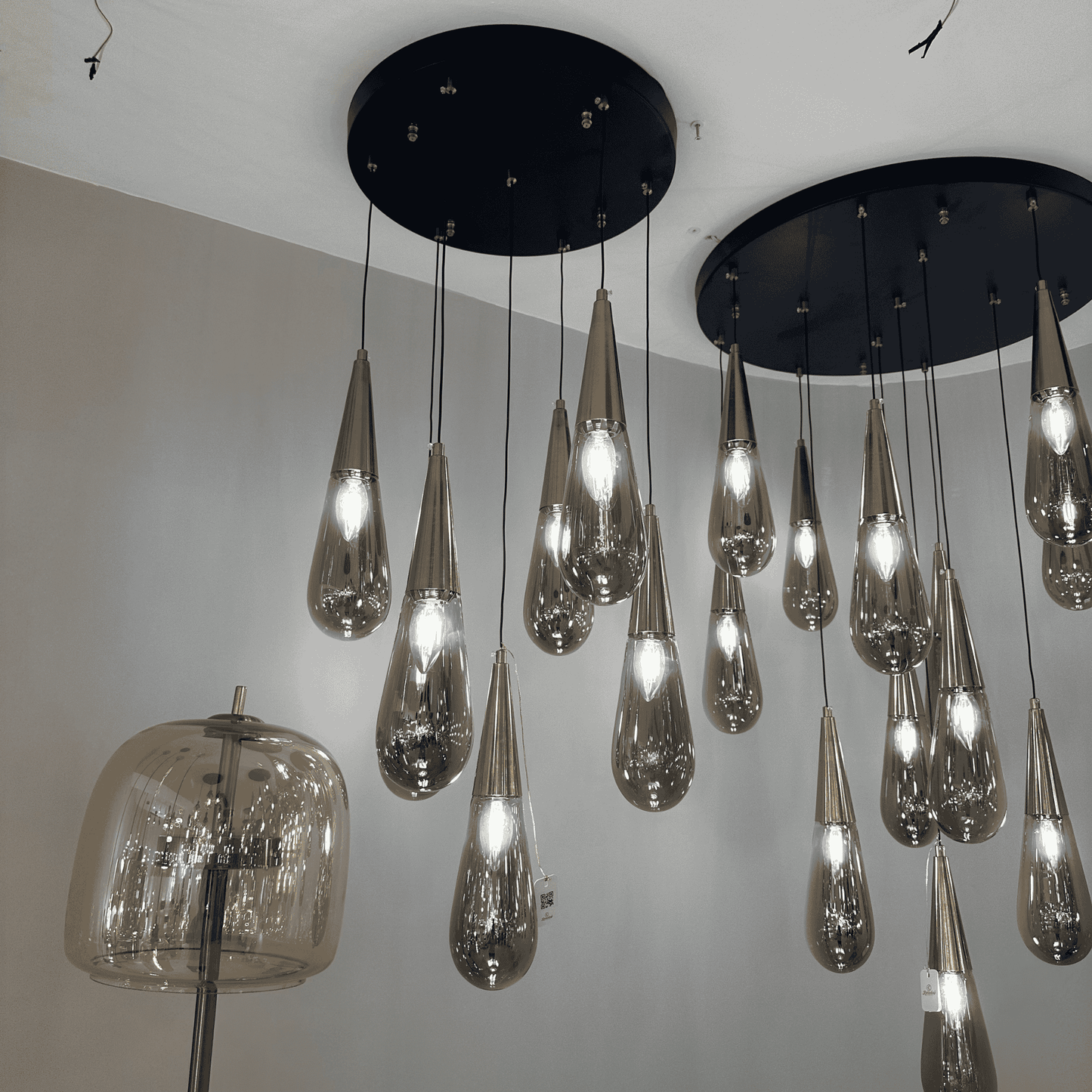 Teardrop pendant lights with reflective finish and black ceiling canopy used in upscale interior design.