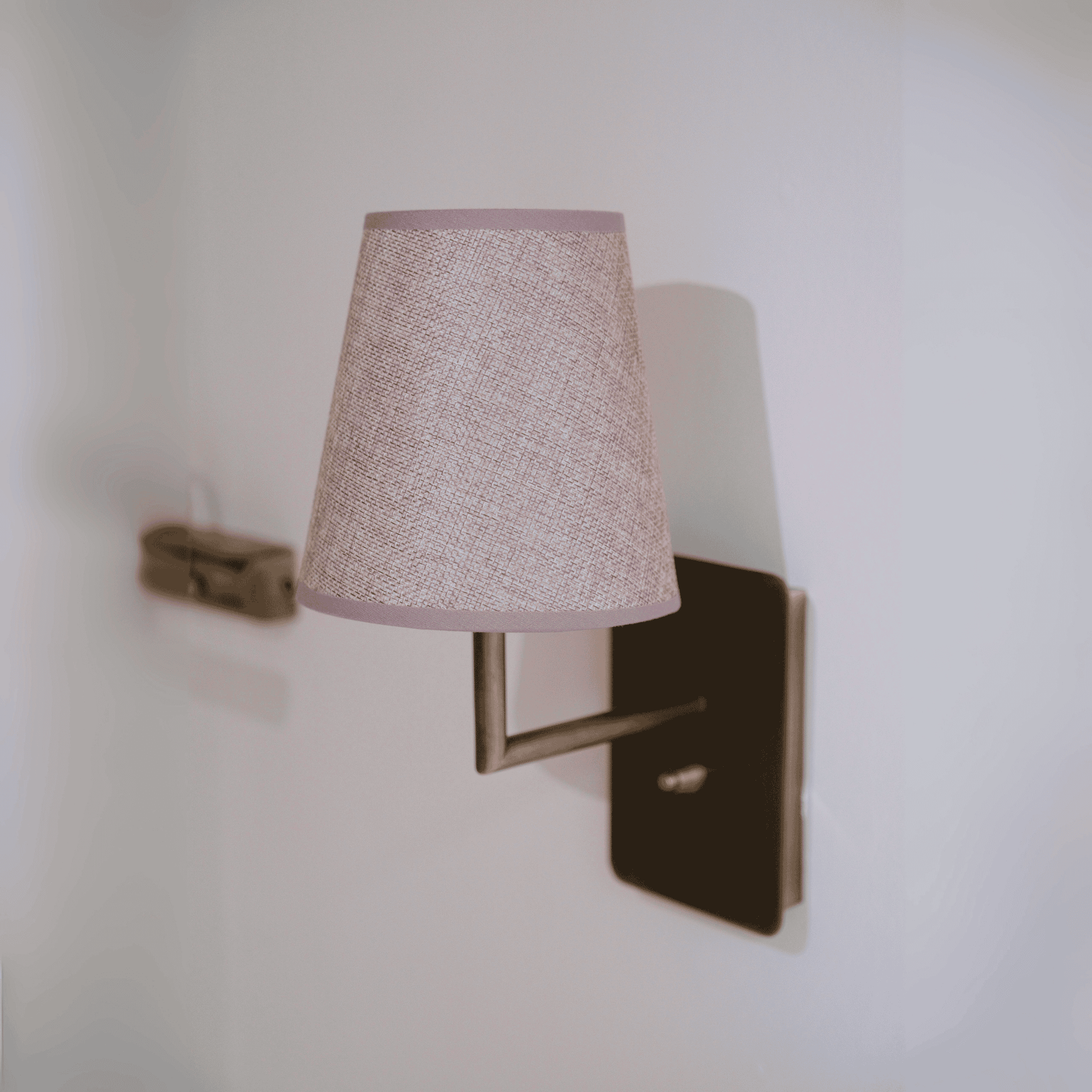 Contemporary wall sconce with linen fabric shade and dark bronze mount for modern interiors.