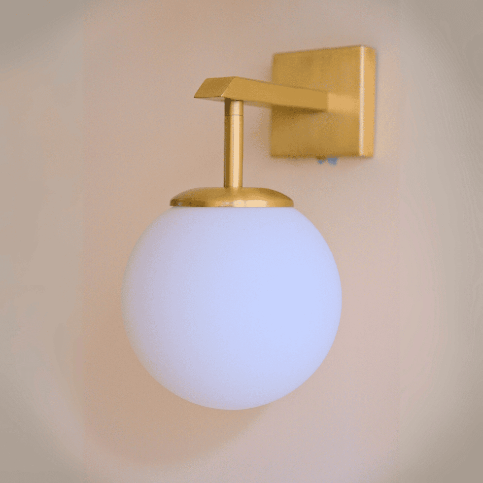 Sleek wall sconce with white globe and brass hardware for refined modern lighting.