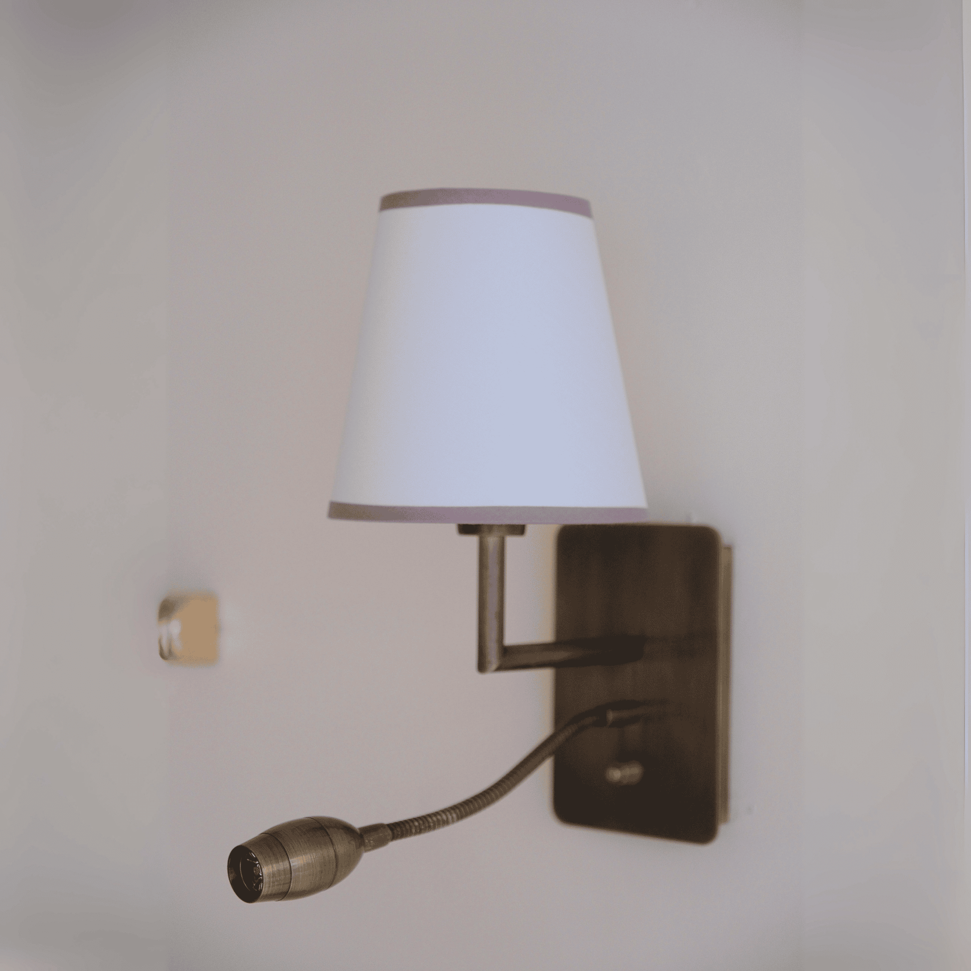 Contemporary sconce with fabric shade and metal gooseneck LED reading light.