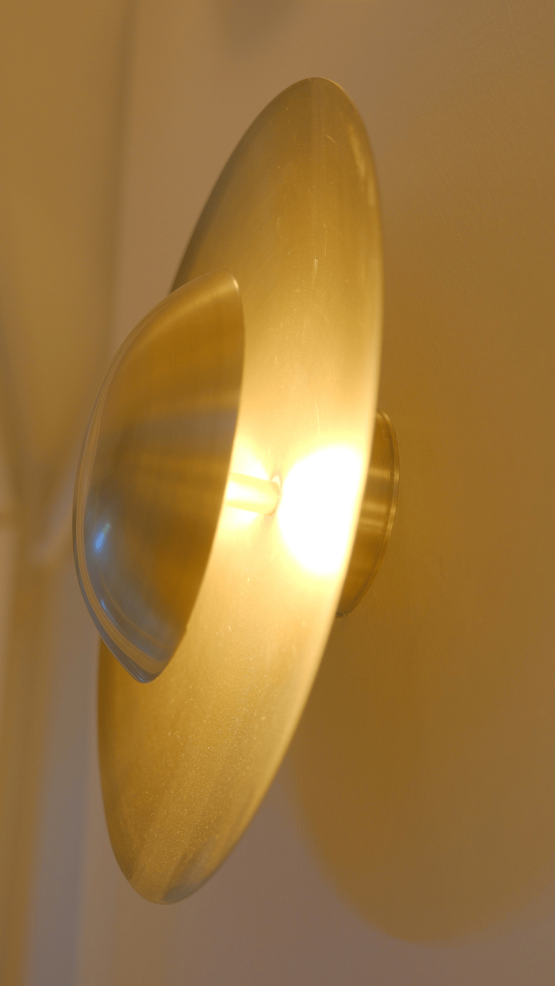 Curved brass wall sconce with convex design casting warm, soft light.