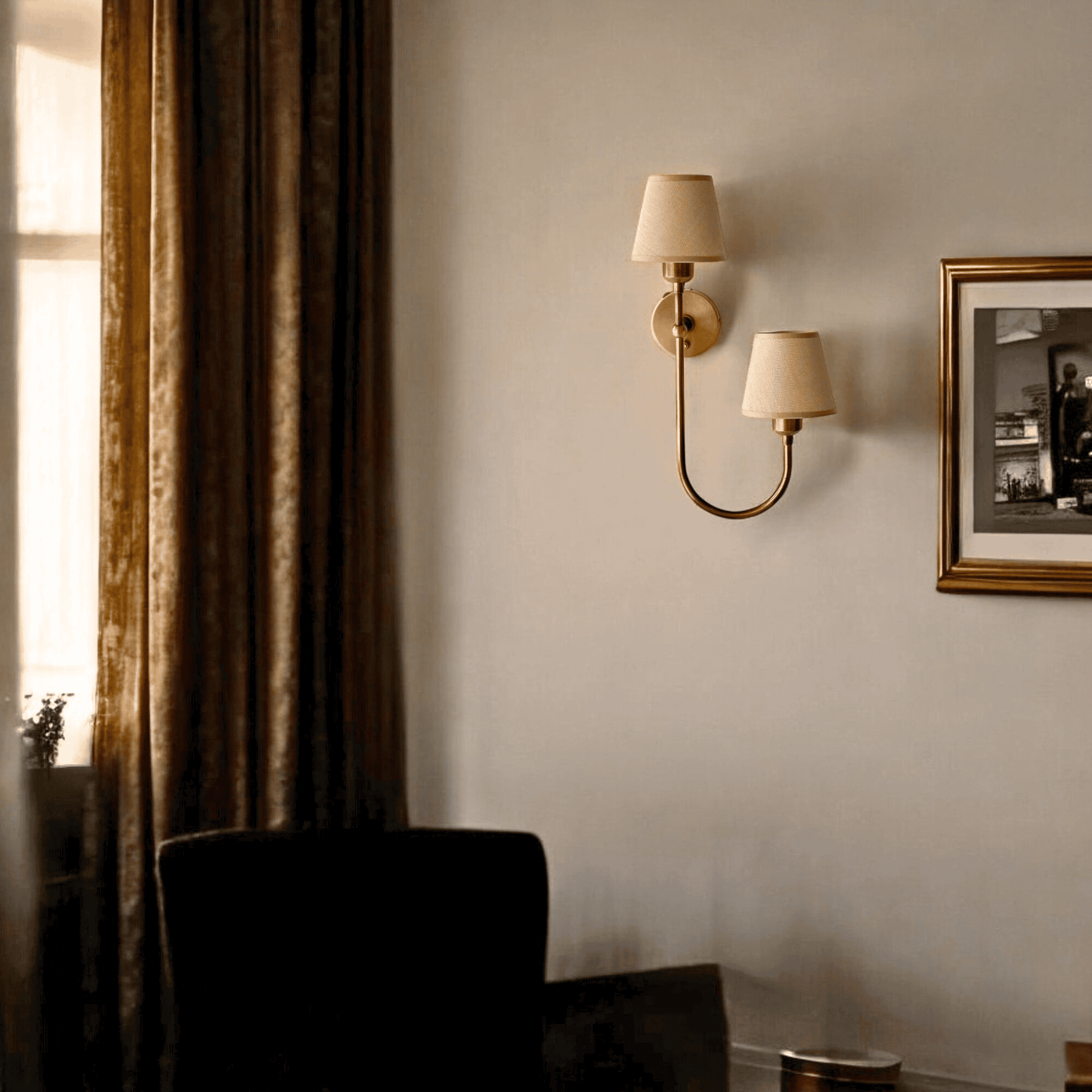 Elegant dual shade fabric wall sconce in aged brass mounted in a cozy living room with warm drapery