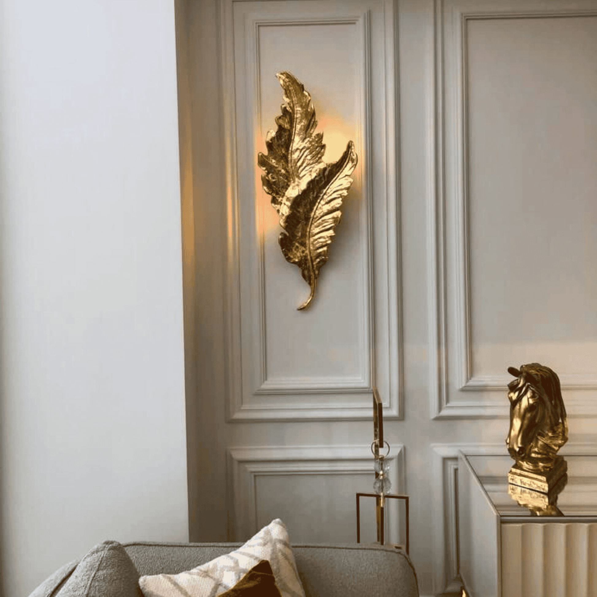 Sculptural gold leaf wall sconce with botanical texture mounted on a soft neutral wall