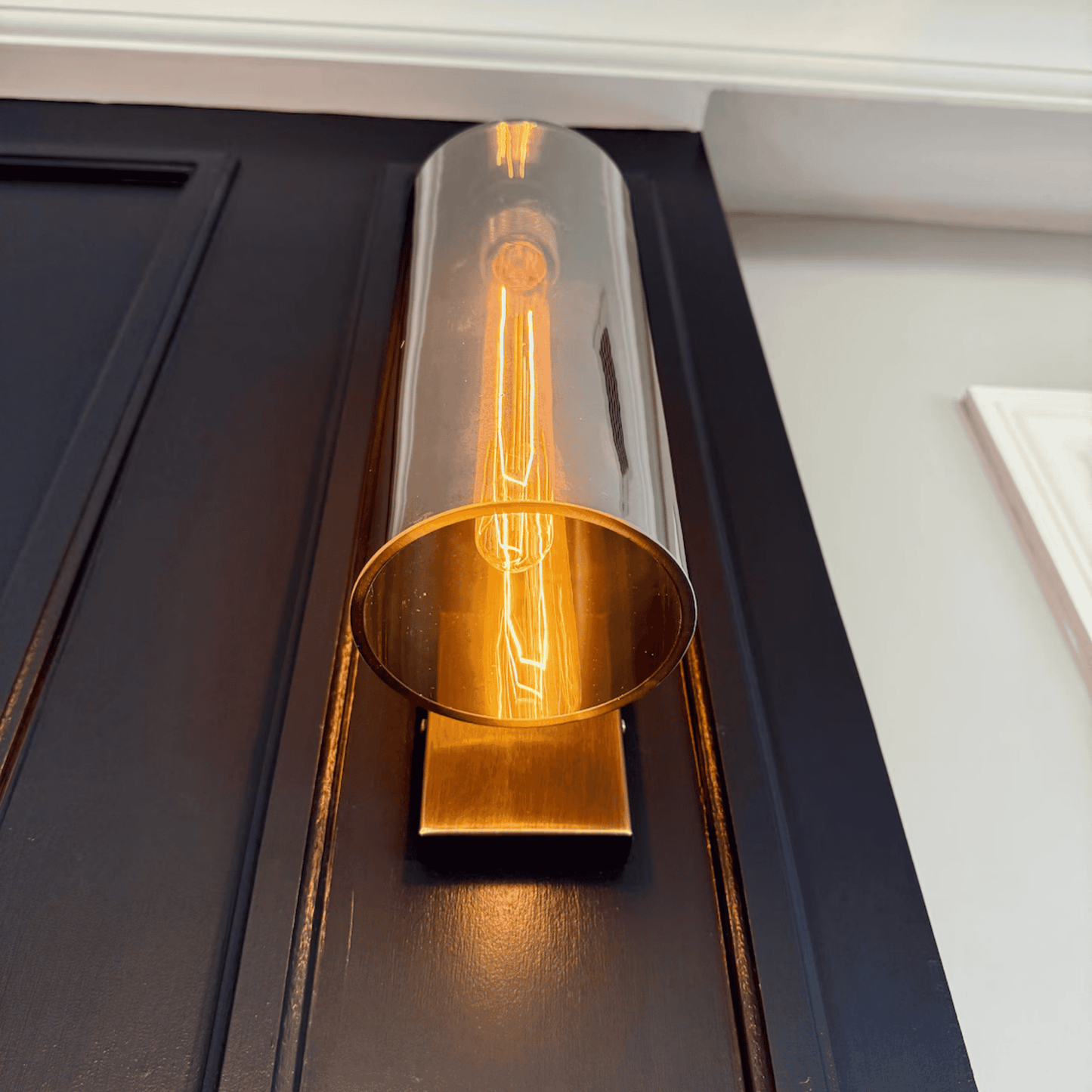 Front view of blown glass wall sconce with antique finish and glowing bulb.