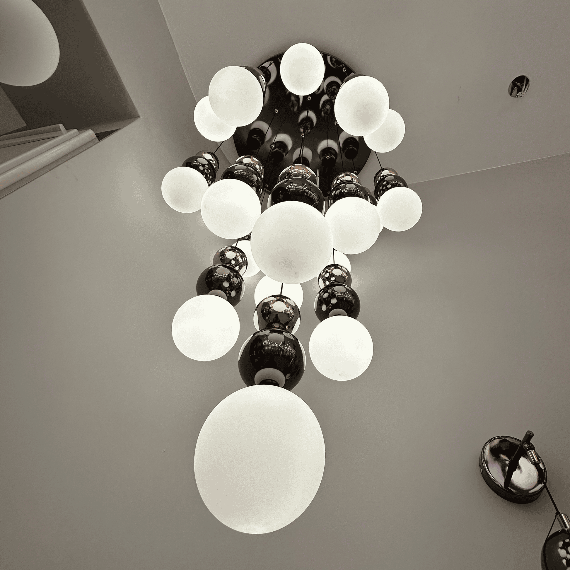 Upward view of a modern frosted glass globe pendant lighting fixture in a cascading chandelier design.