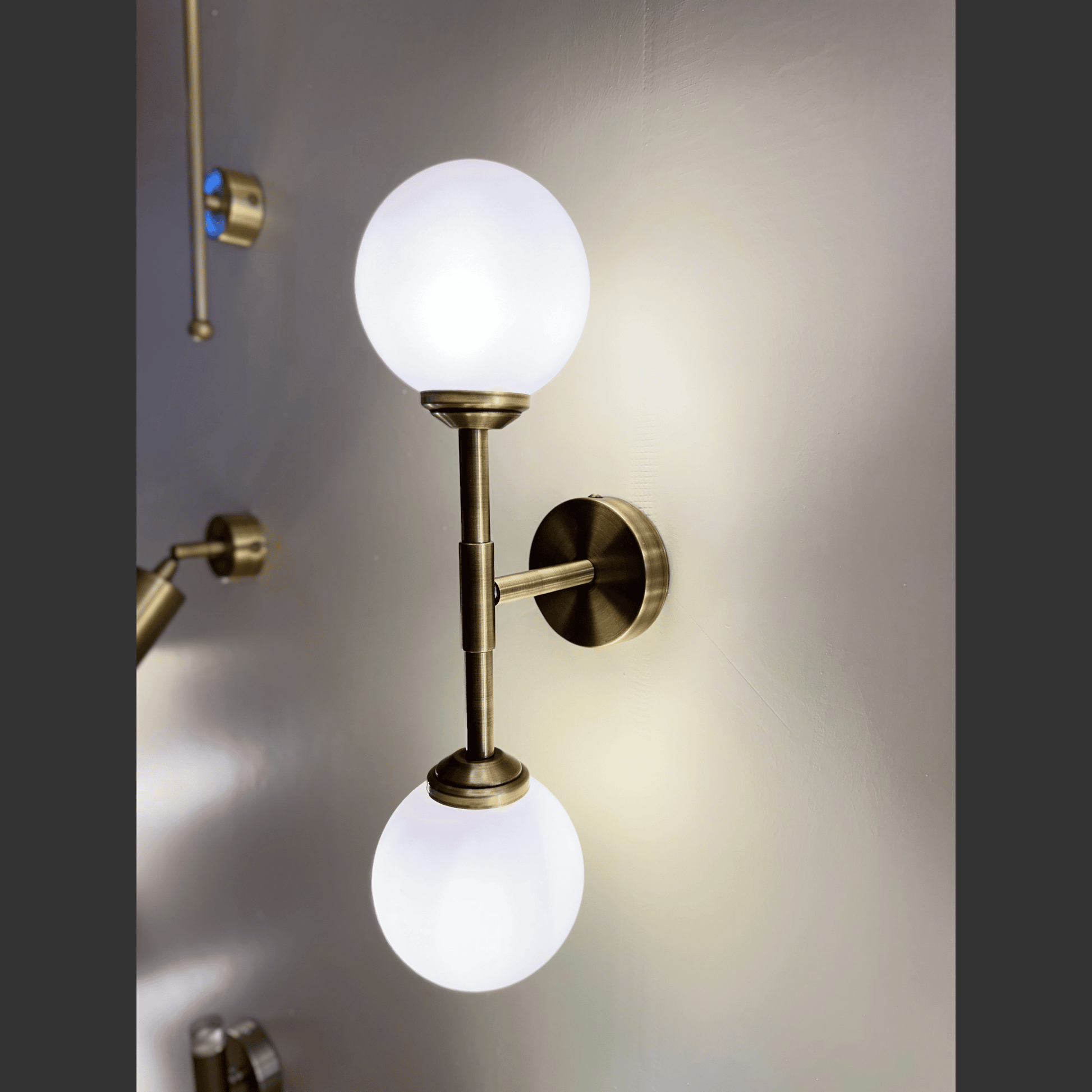 Wall-mounted lamp with two glass globe lights on a neutral background