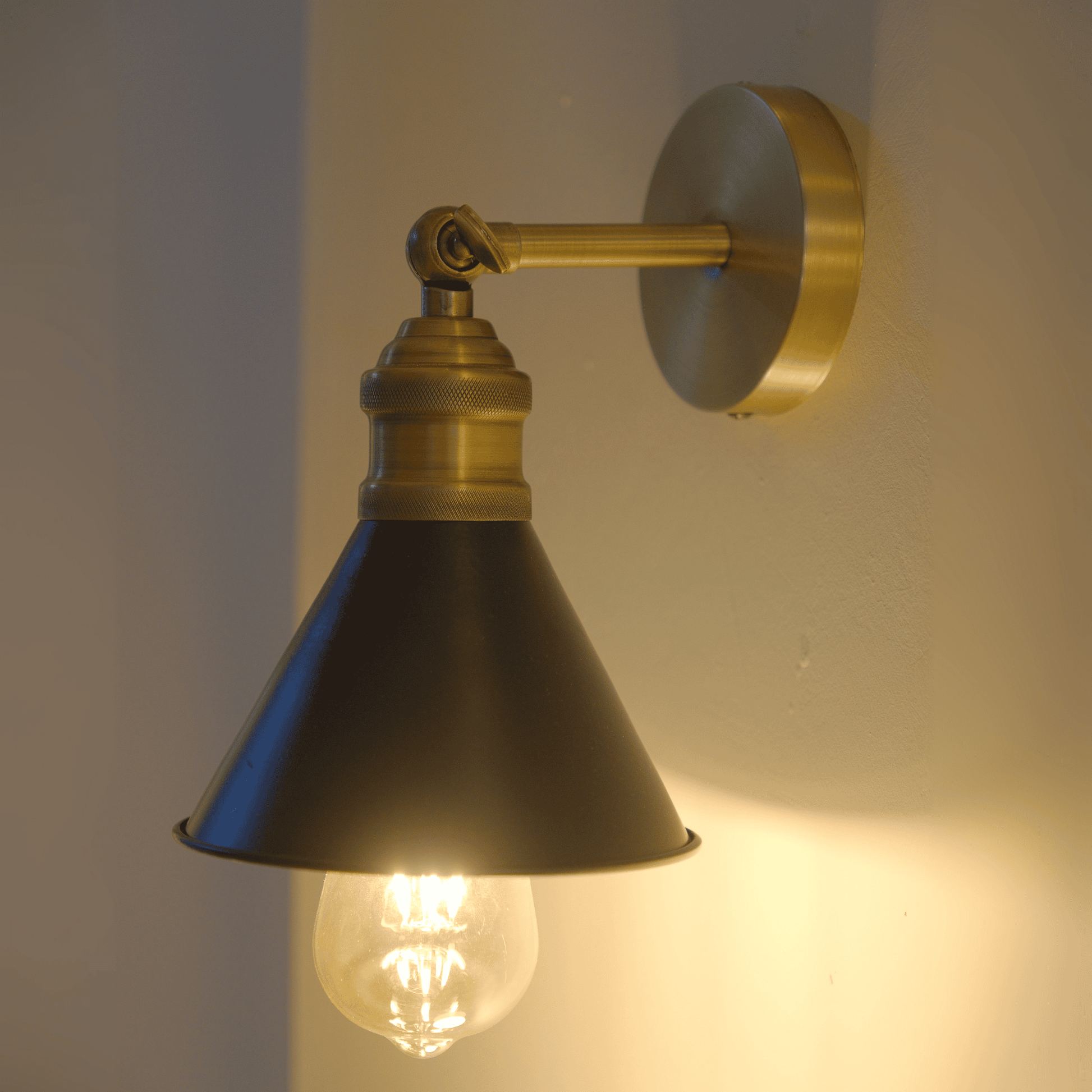 Lit brass and black wall sconce casting warm glow against the wall.