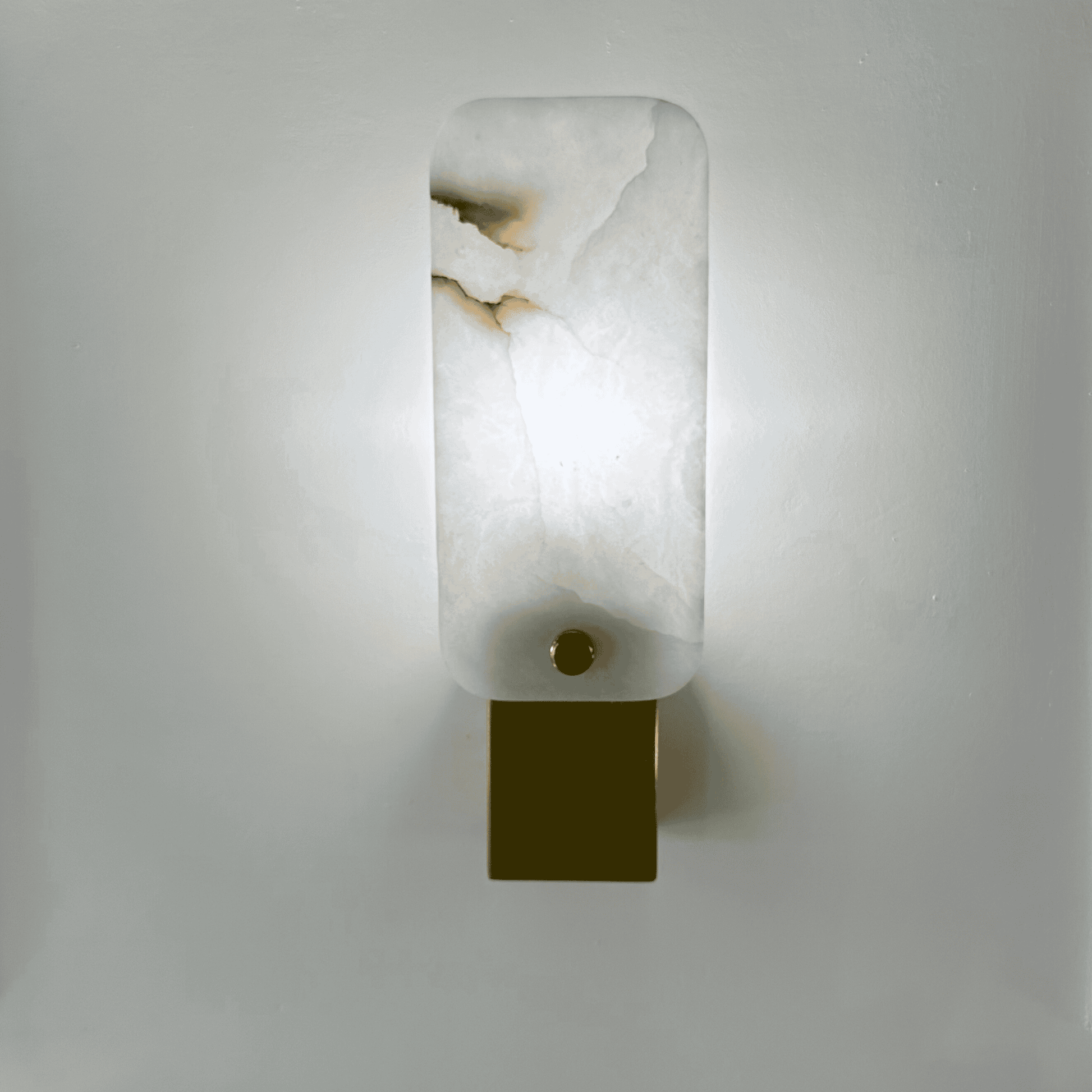 Glowing white square marble wall lamp with soft light and brass detail.