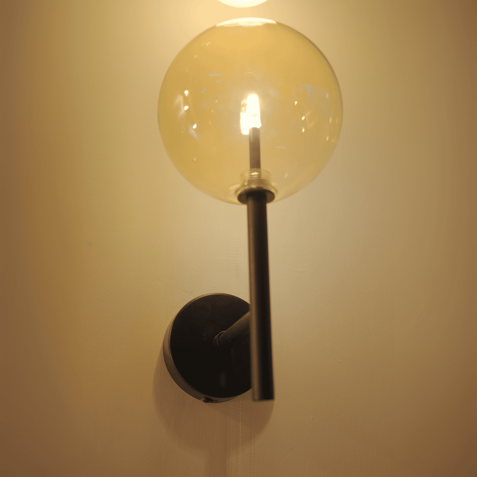 Wall-mounted hallway sconce with clear glass globe and black metal fixture.