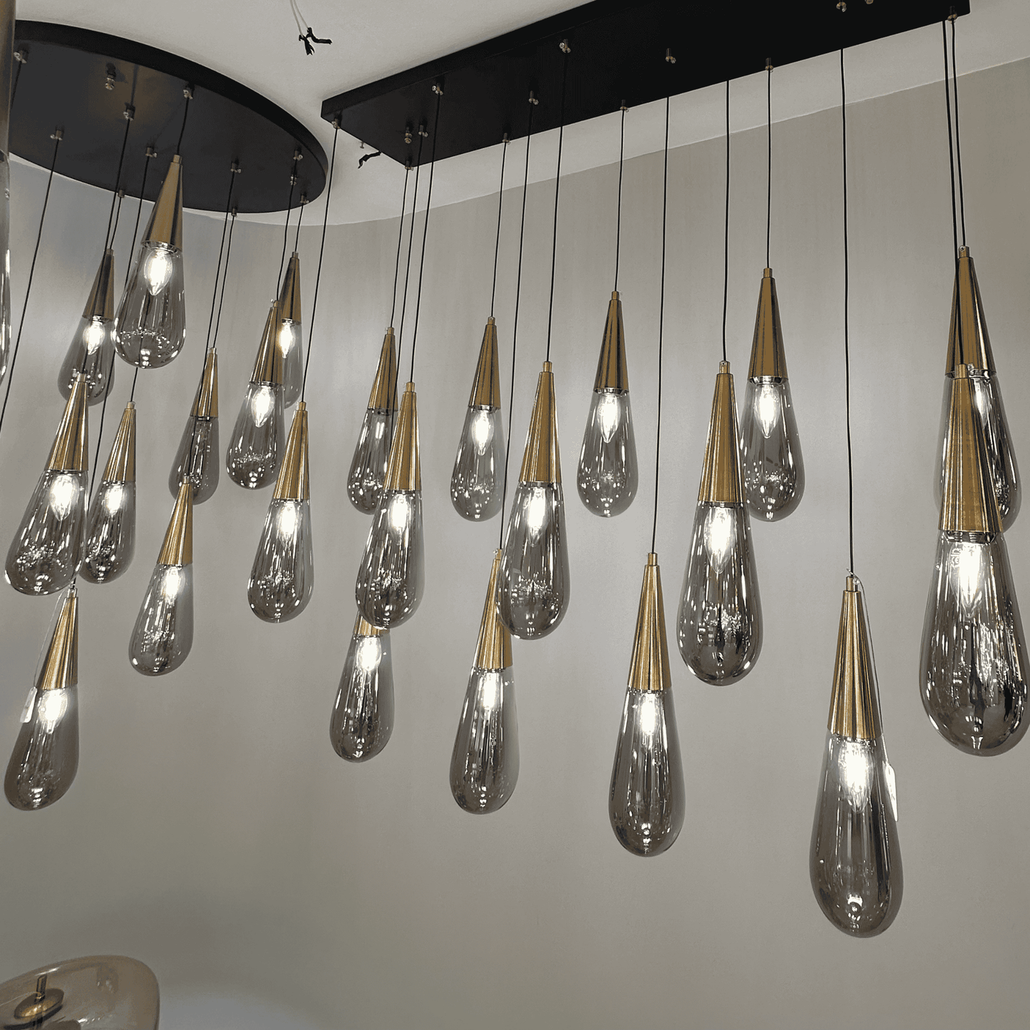 Row of gold-accented teardrop glass pendant lights suspended from a rectangular black fixture.