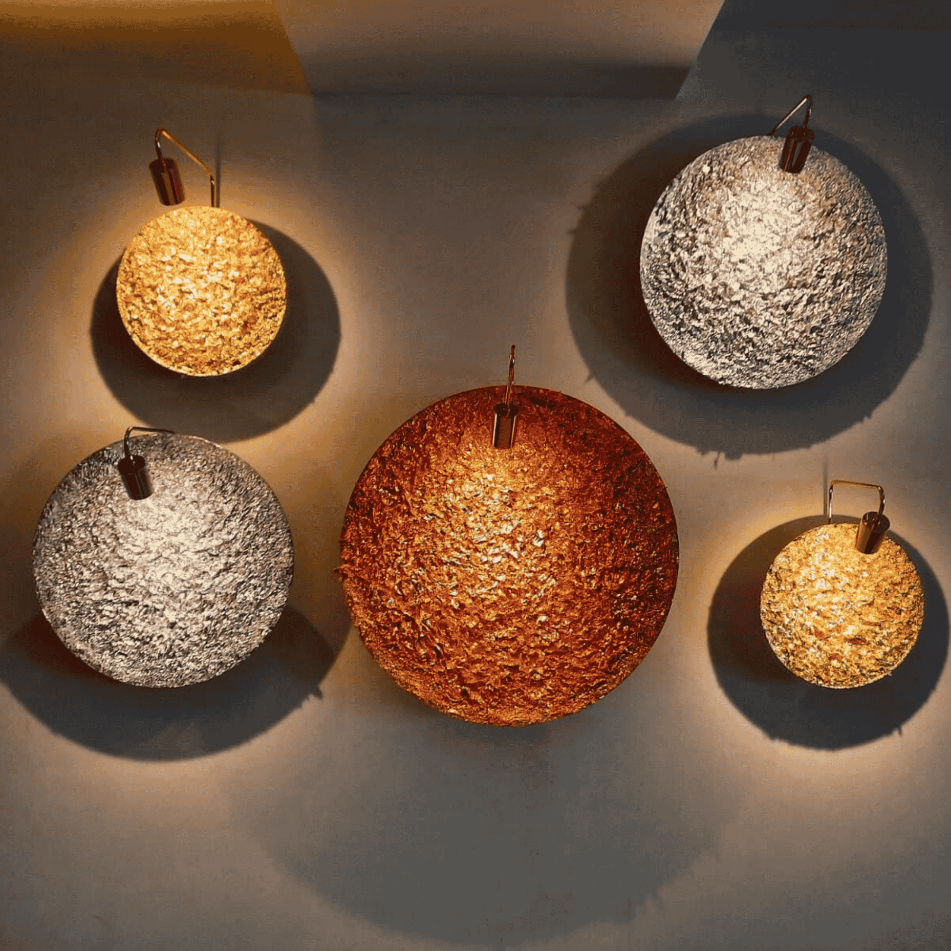 Sculptural brass wall sconce with a textured circular face, glowing softly on a dark interior wall