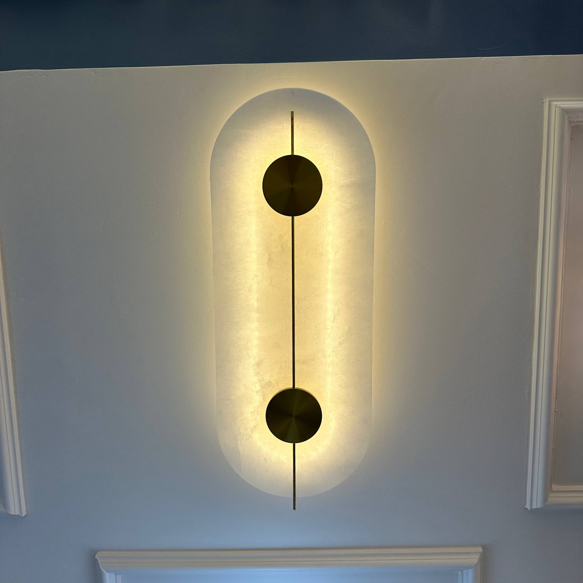 Wall-mounted luxury alabaster light fixture with brass accents and ambient glow.