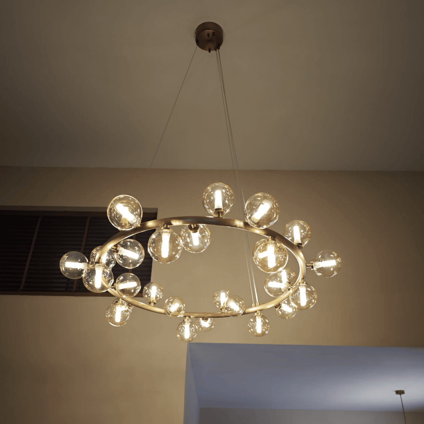 Modern brass chandelier with LED bulbs inside glass globes, suspended from the ceiling with minimal cables.