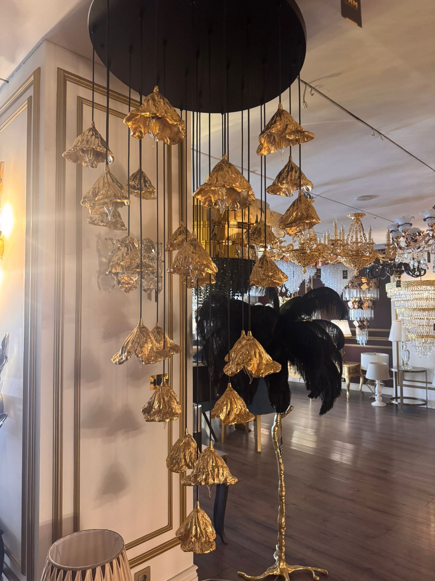 Cascading pure brass leaf pendant lights on display in an upscale lighting showroom.