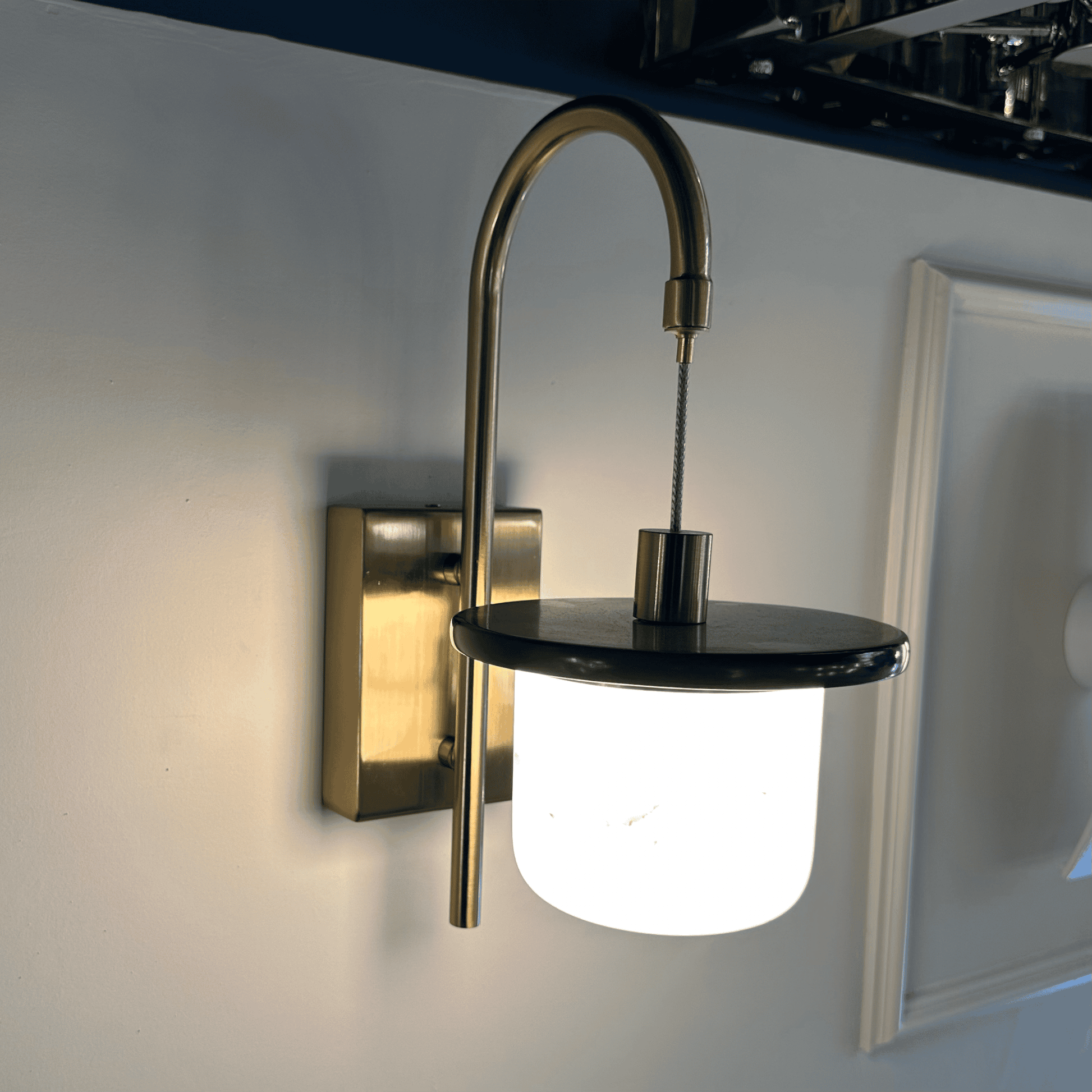 Brightly glowing marble sconce wall light with alabaster shade and brass hardware.