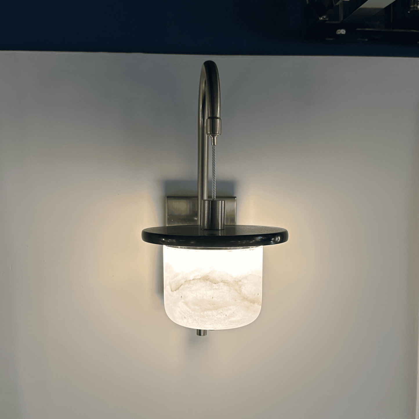 Glowing marble sconce wall light with alabaster shade seen from the front.