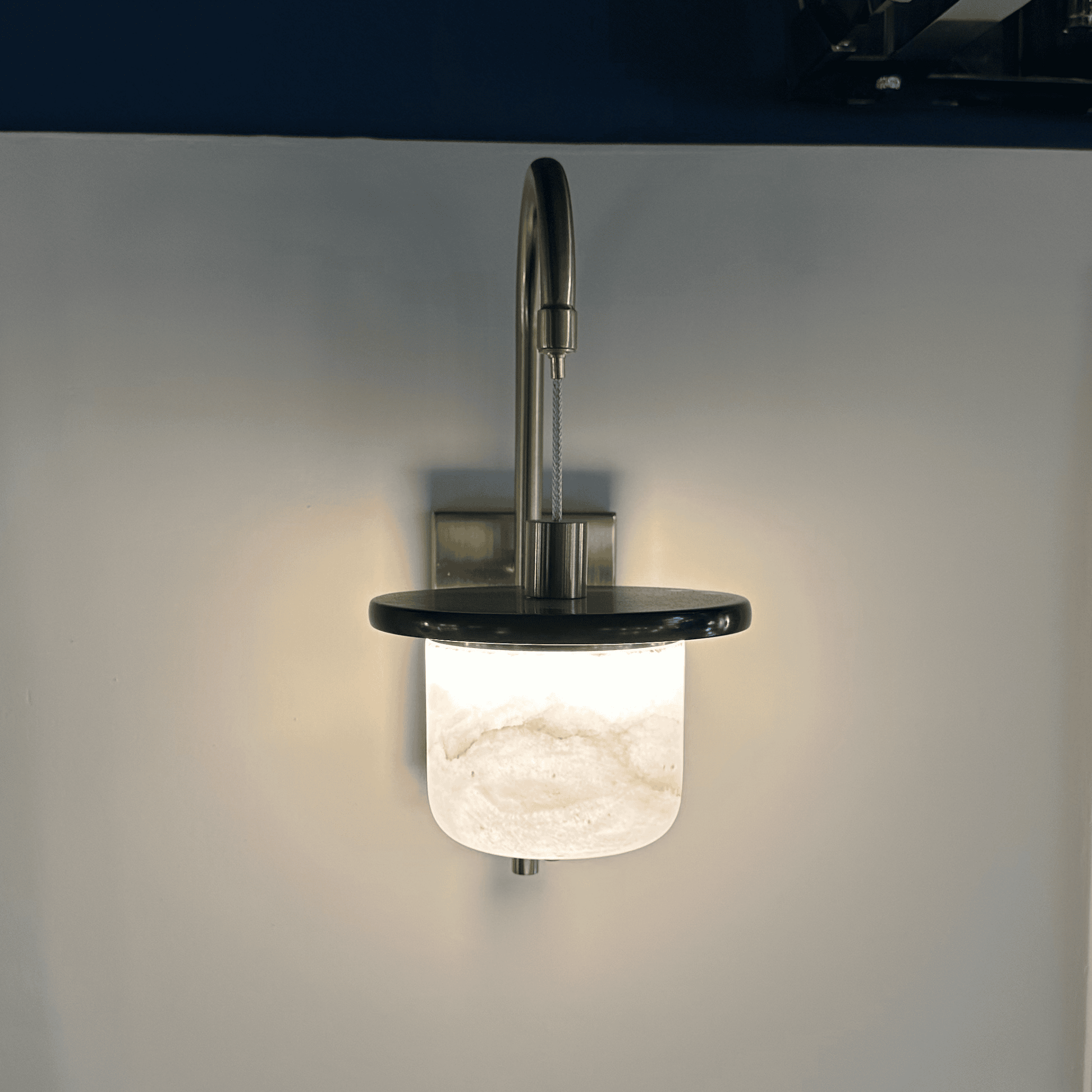 Glowing marble sconce wall light with alabaster shade seen from the front.
