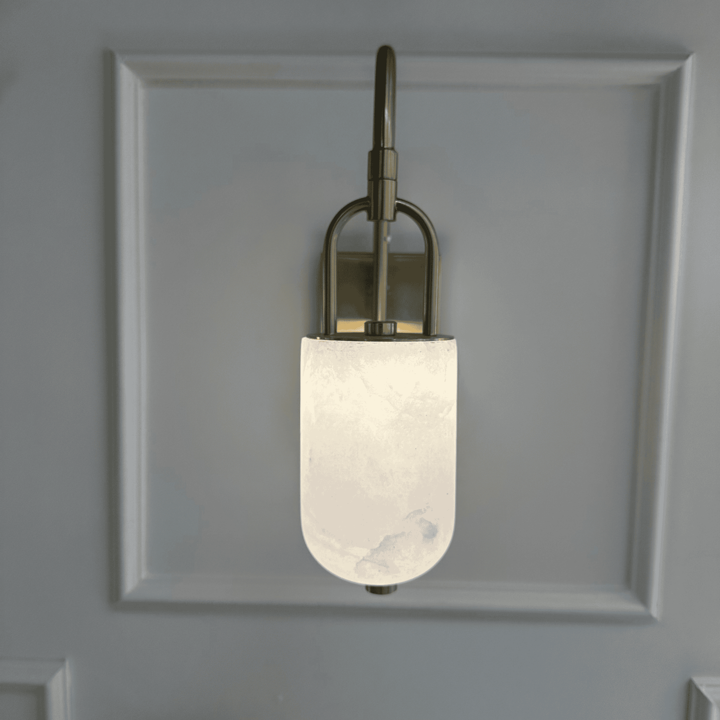 Front view of wall-mounted marble sconce with frosted alabaster and brass detailing.