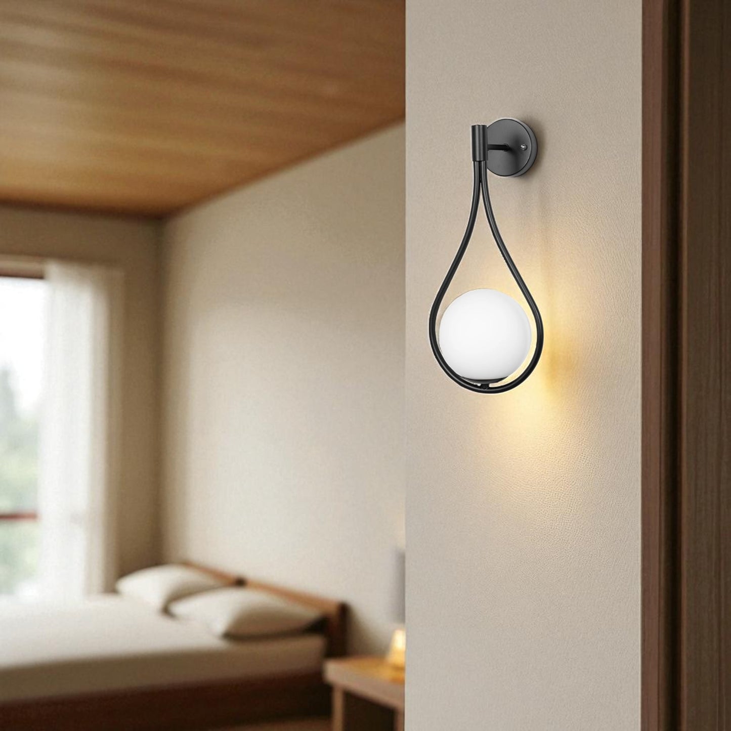 Minimalist matte black teardrop wall sconce with white globe, mounted on a bedroom wall.