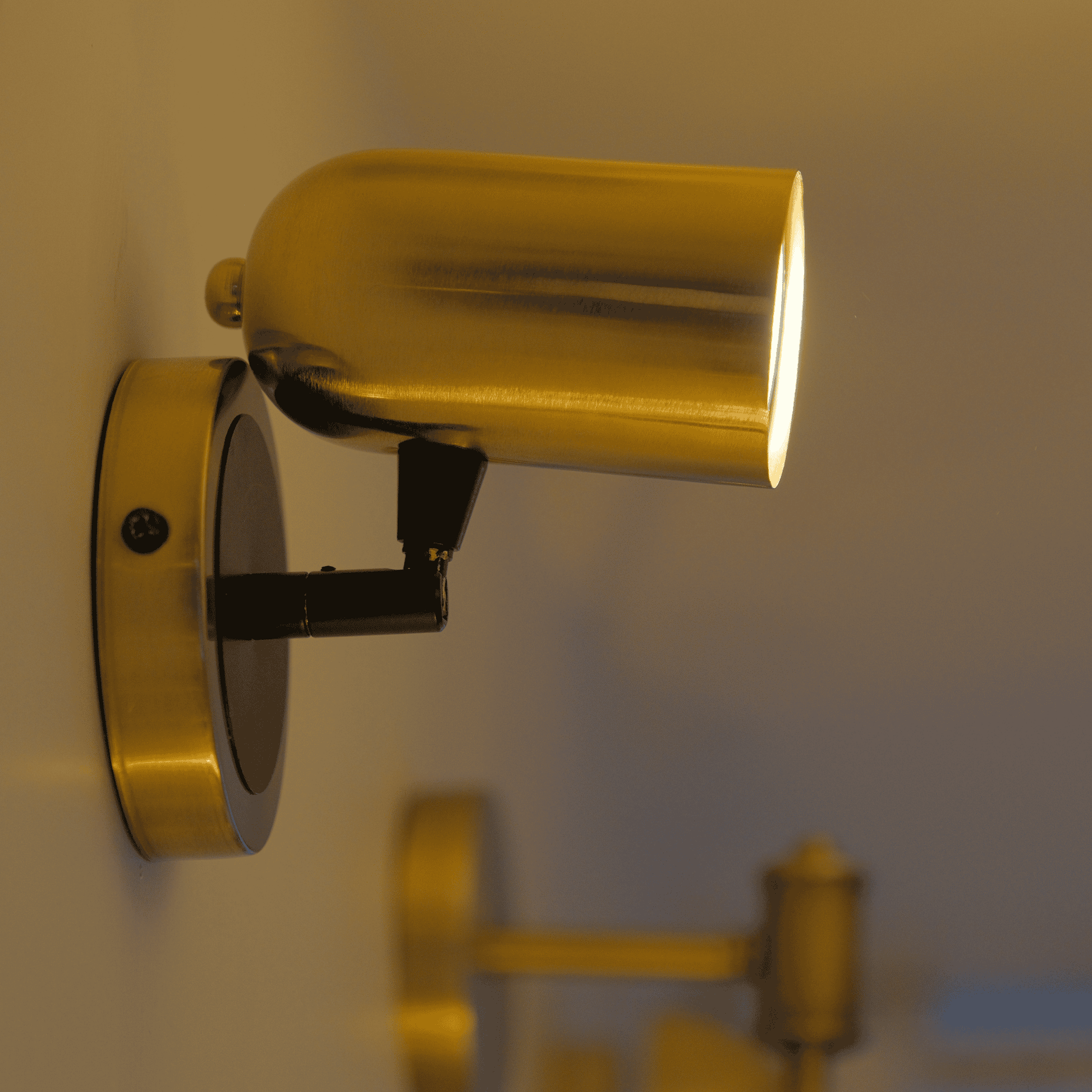 Minimalist brass and black wall sconce with cylinder shade and adjustable head.