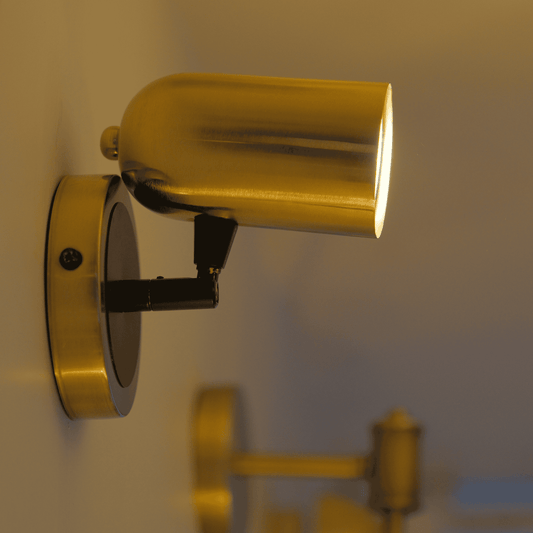 Minimalist brass and black wall sconce with cylinder shade and adjustable head.