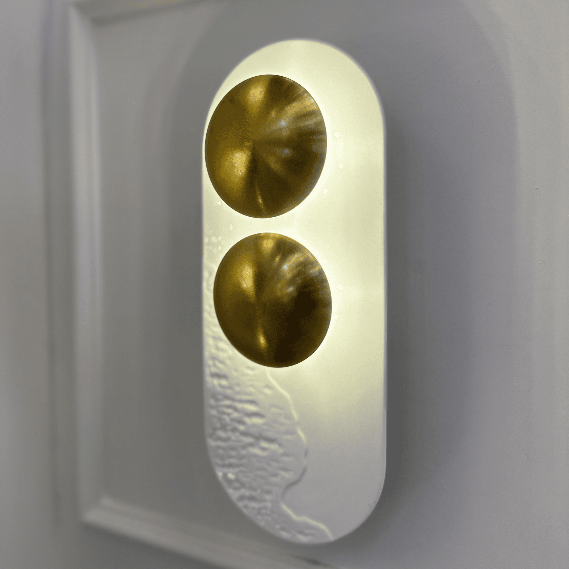 Close-up of white resin and brass minimalist LED wall sconce ideal for modern interiors.