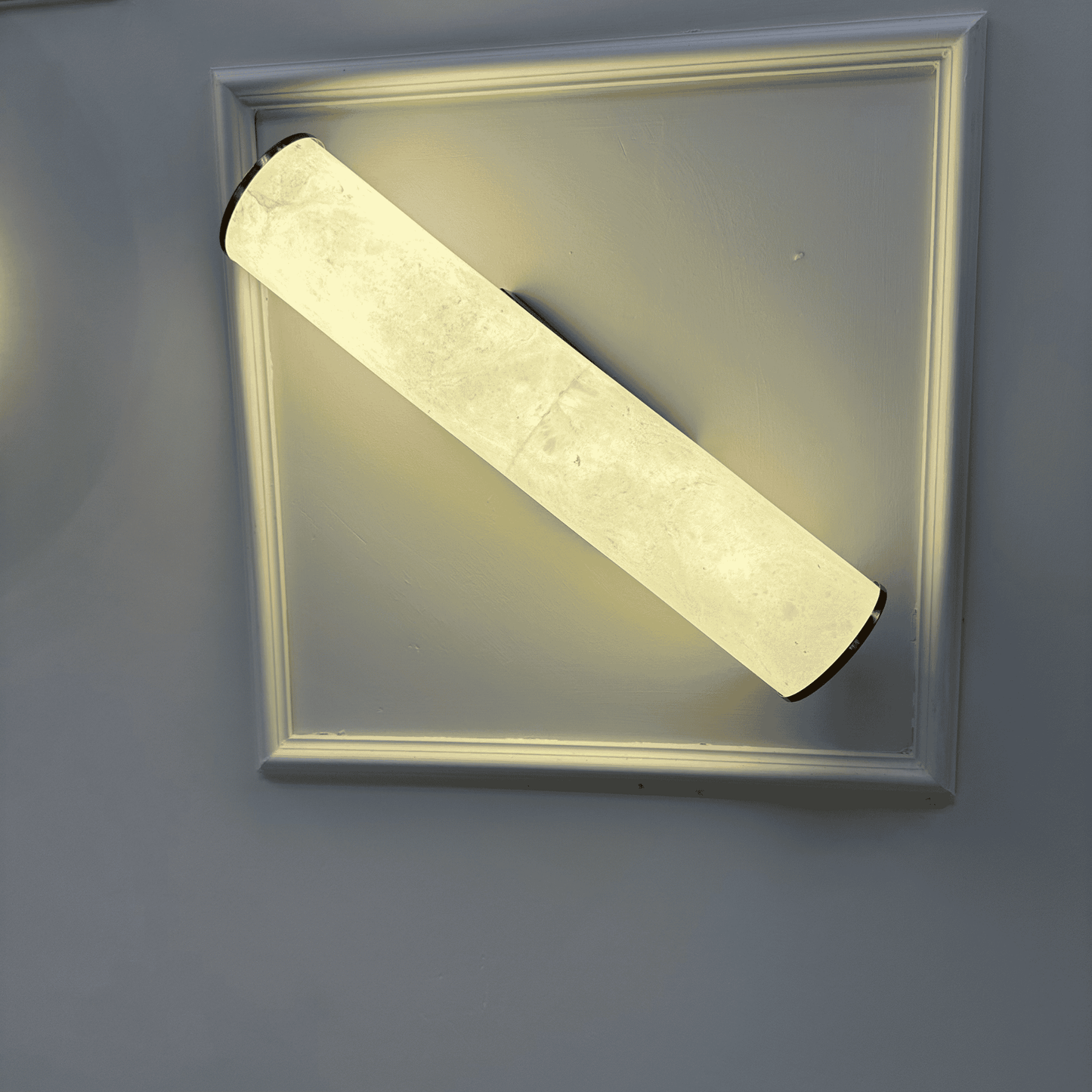 Minimalist horizontal alabaster wall sconce with natural stone texture and diffused glow.