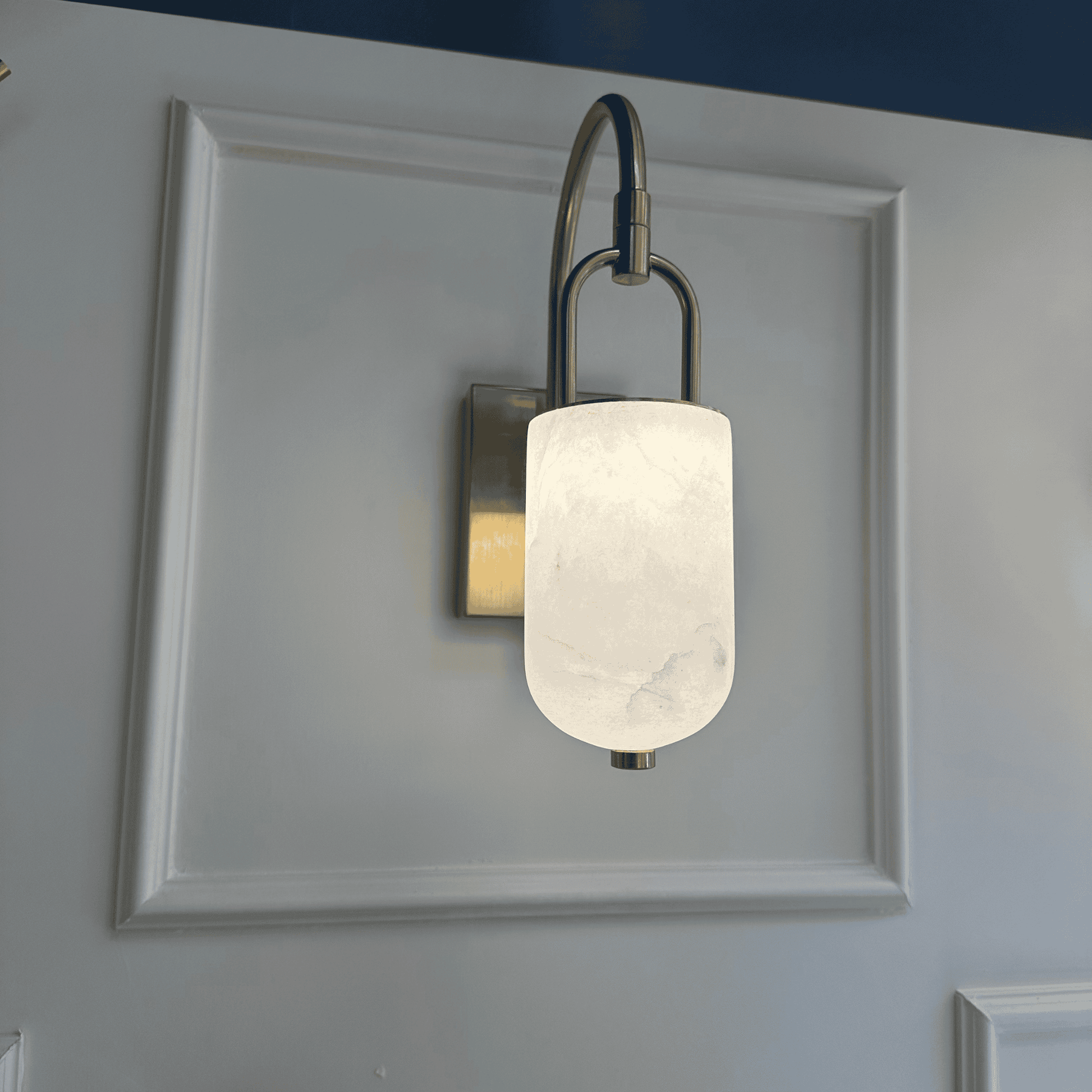 Decorative marble wall sconce with cylindrical alabaster shade and brushed brass arm.