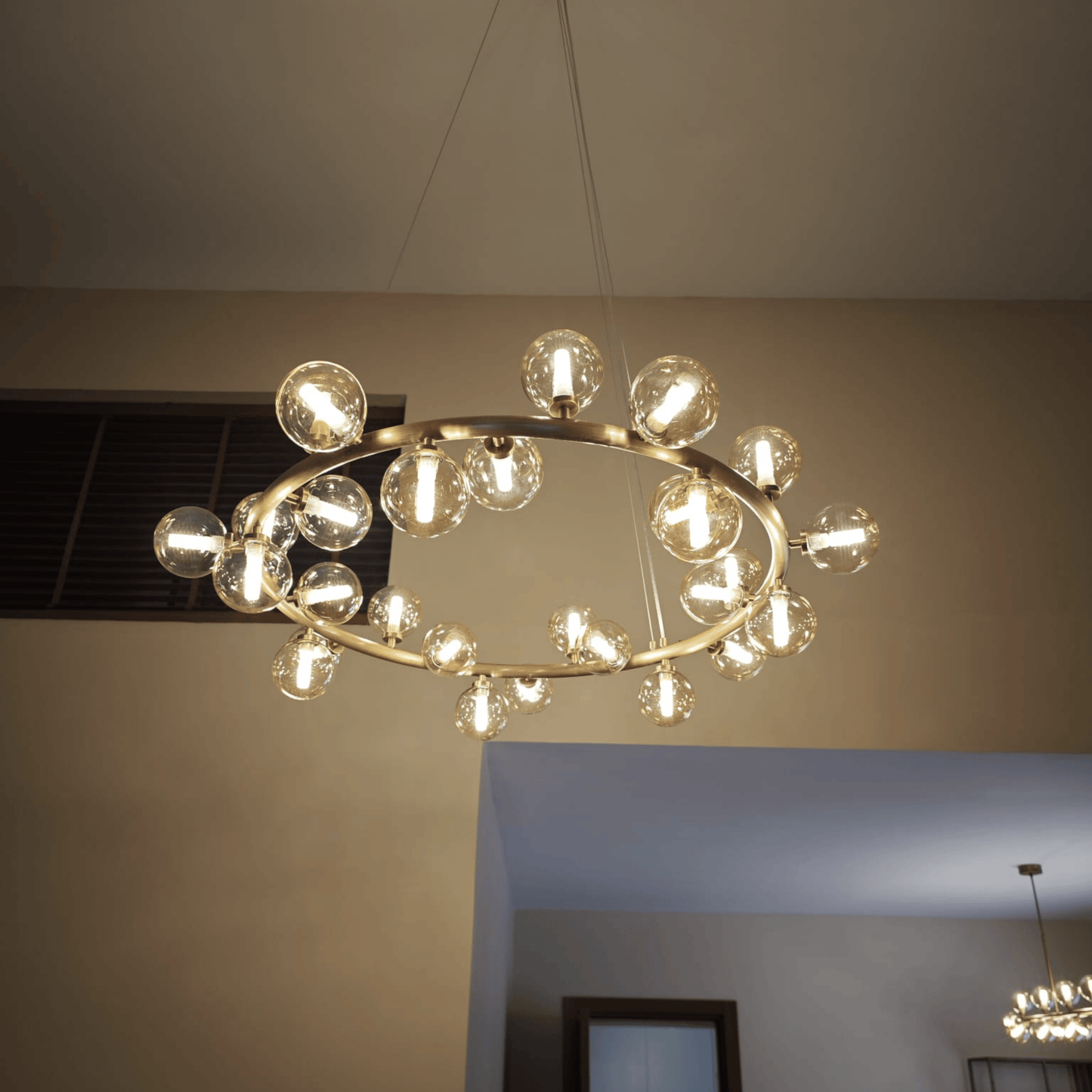 Brass ring chandelier with clear glass globes suspended from the ceiling, providing warm modern ambient lighting.