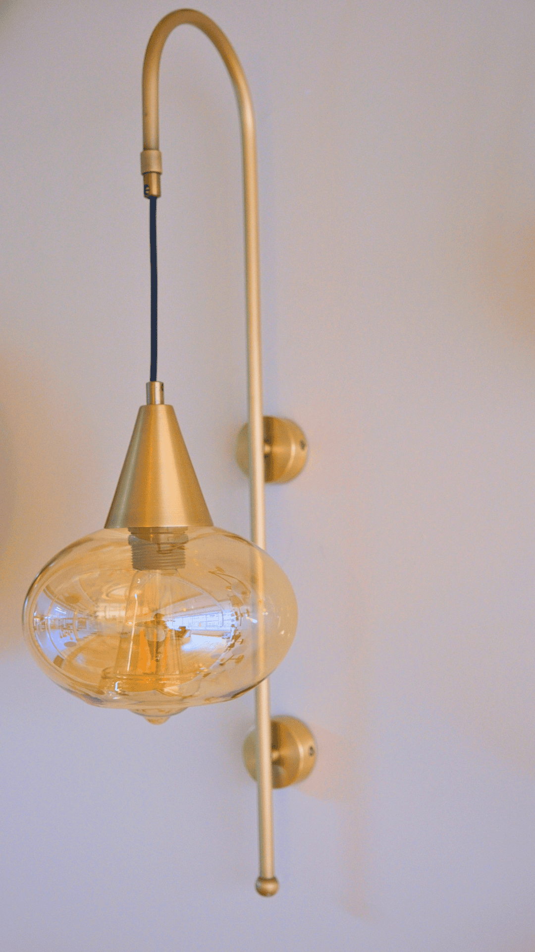 Daylight view of modern brass wall sconce with clear glass globe and sleek mount.