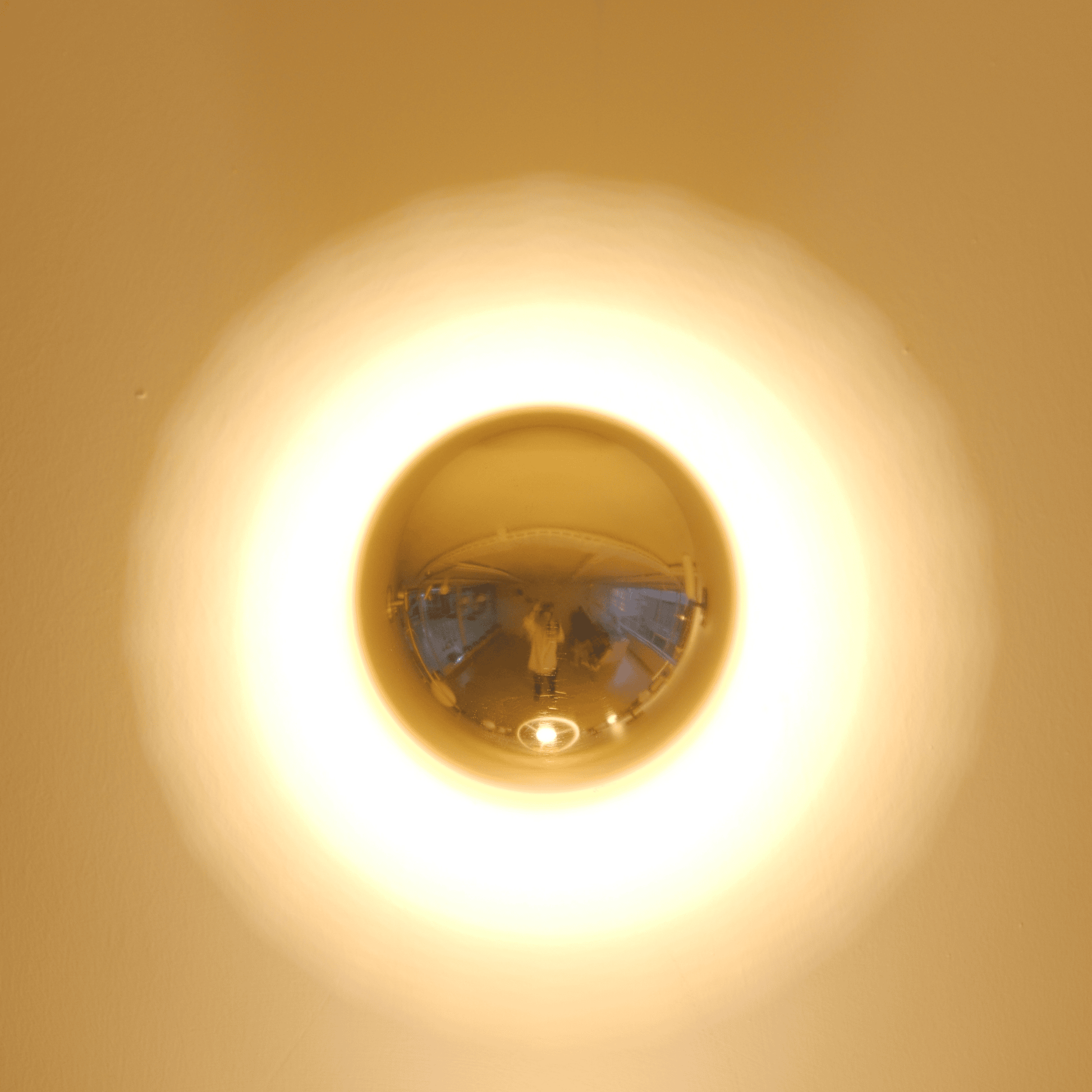 A brass wall sconce emits a circular ambient glow, ideal for modern interior lighting design.