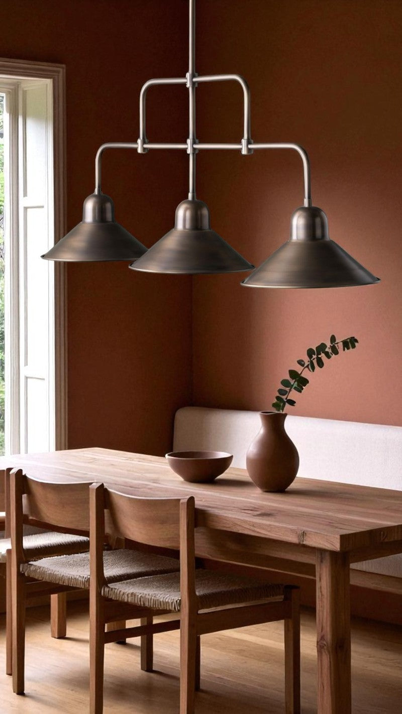 Bronze triple pendant light adds industrial style above a wooden dining table in a cozy modern dining room.