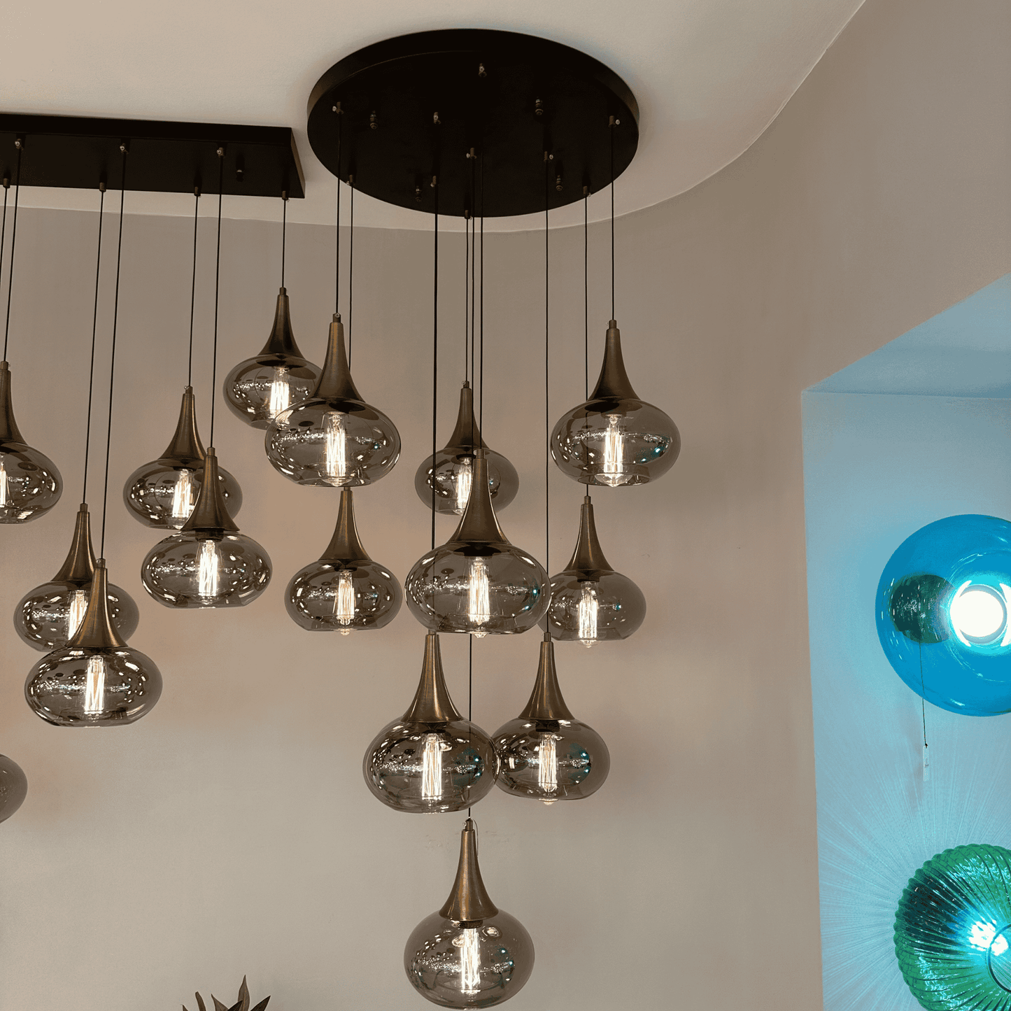 Cluster of modern pendant lights with glass globes and bronze accents installed in a staircase ceiling design.