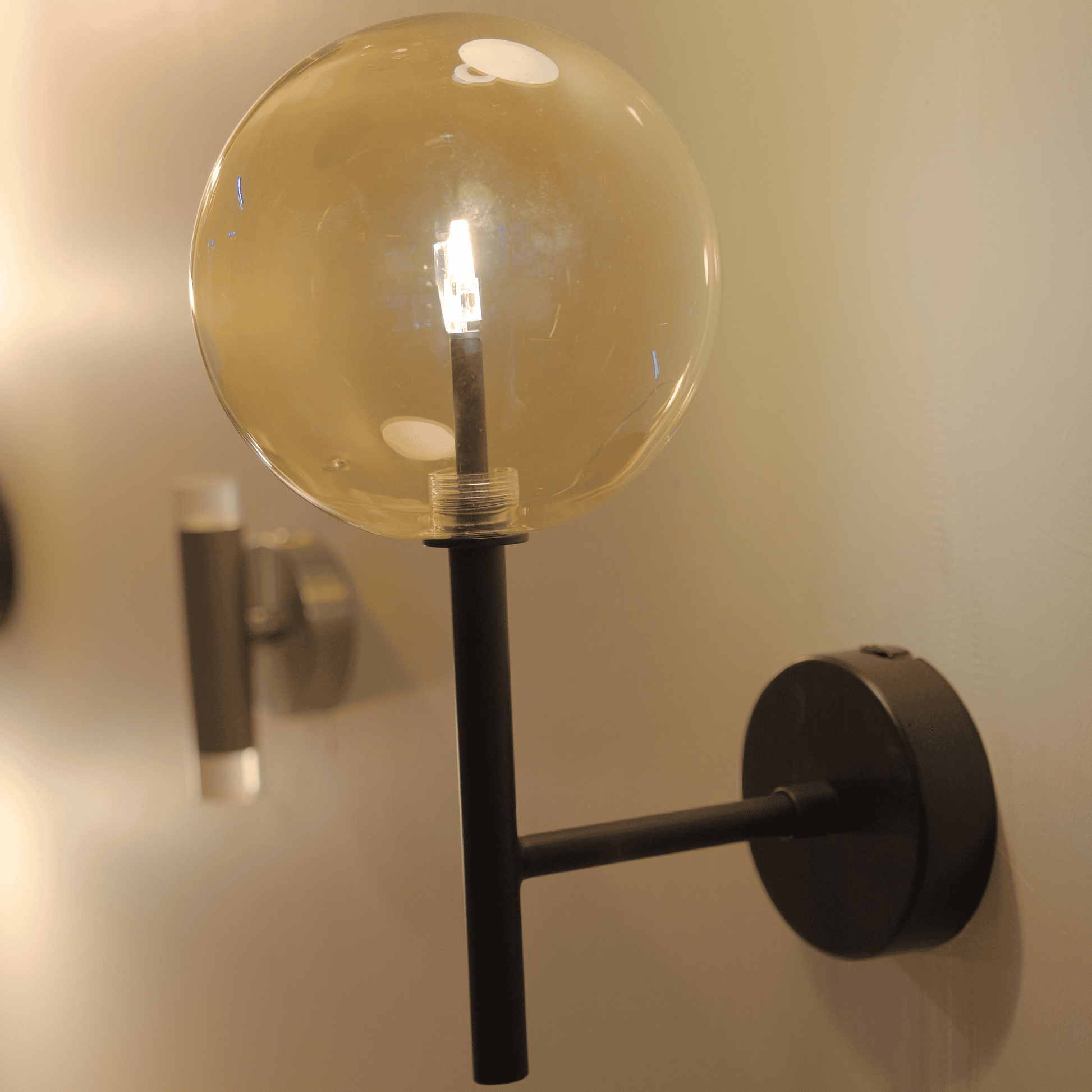 Tall black arm wall sconce with clear LED globe in a contemporary interior.
