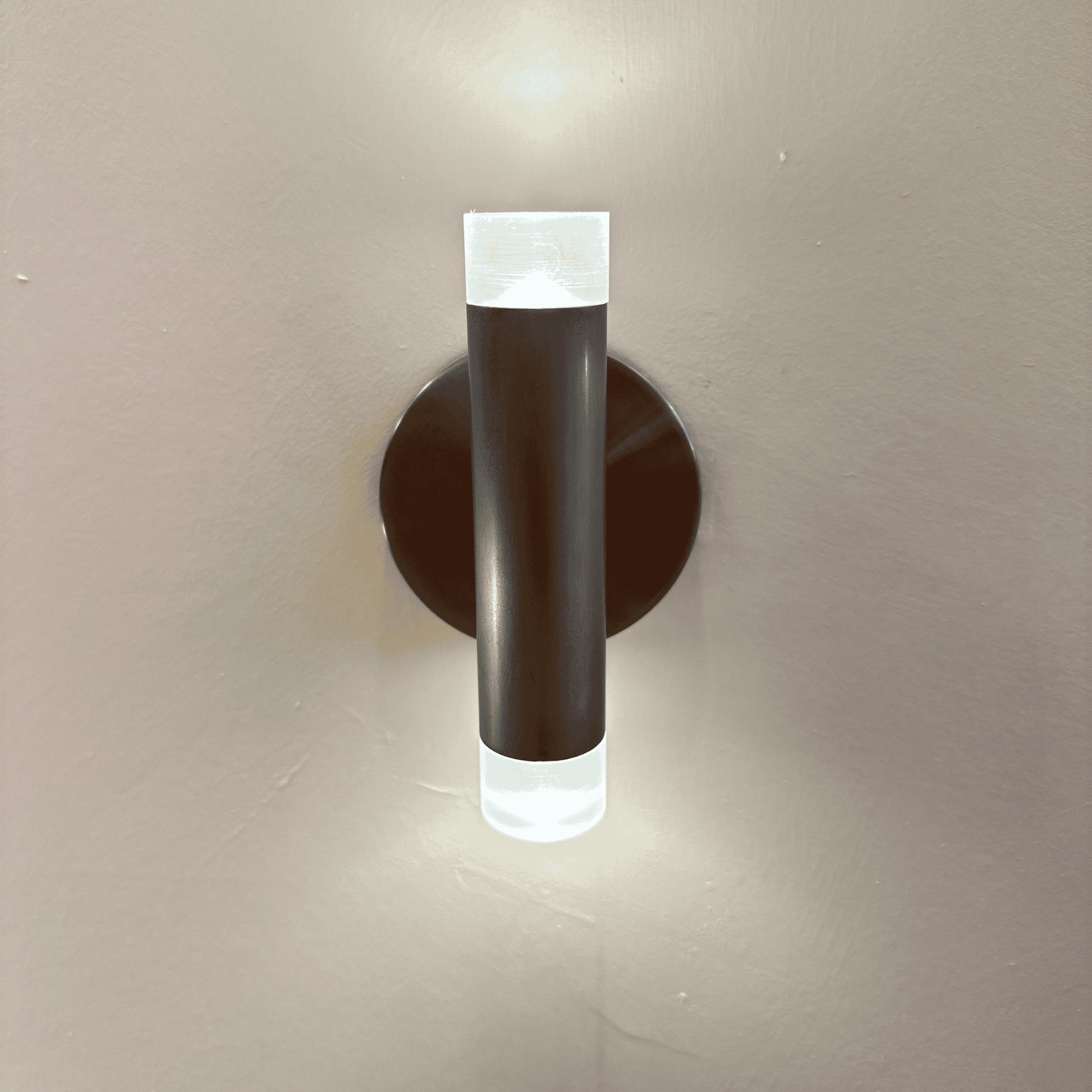 Modern LED wall sconce with brushed nickel finish and frosted acrylic ends, mounted on a neutral wall for soft ambient lighting.
