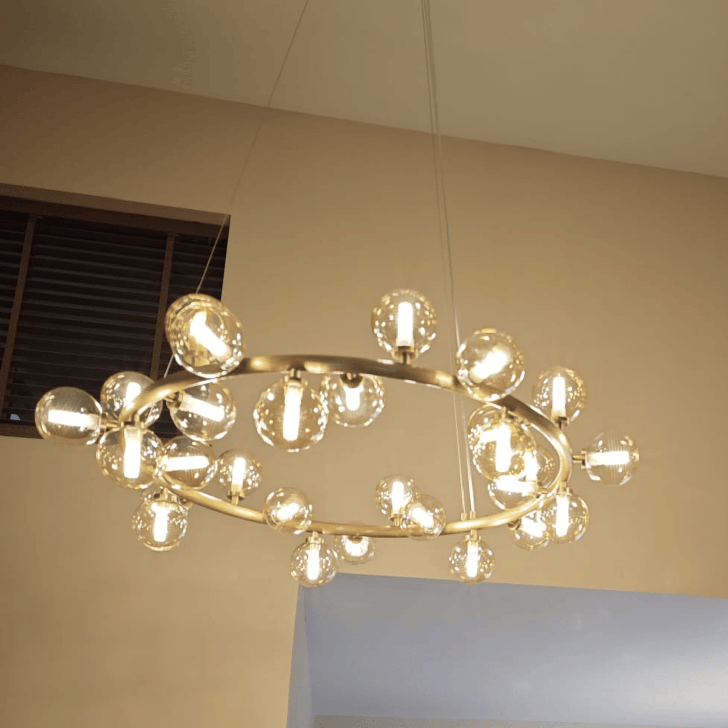 Suspended brass chandelier with clear globe bulbs, offering modern lighting in a clean interior design.