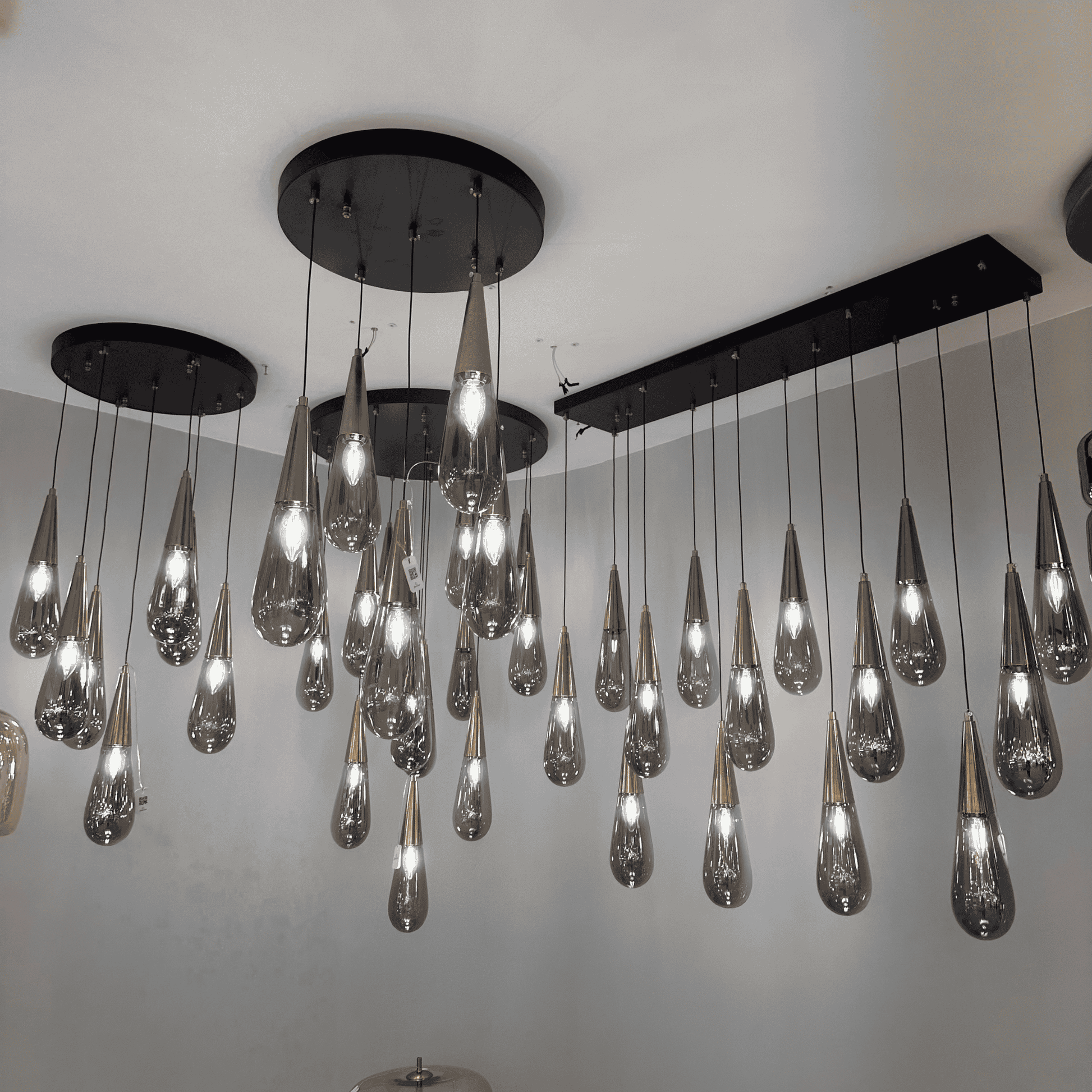 Cluster of teardrop-shaped glass pendant lights with black ceiling mounts, ideal for modern interior lighting.