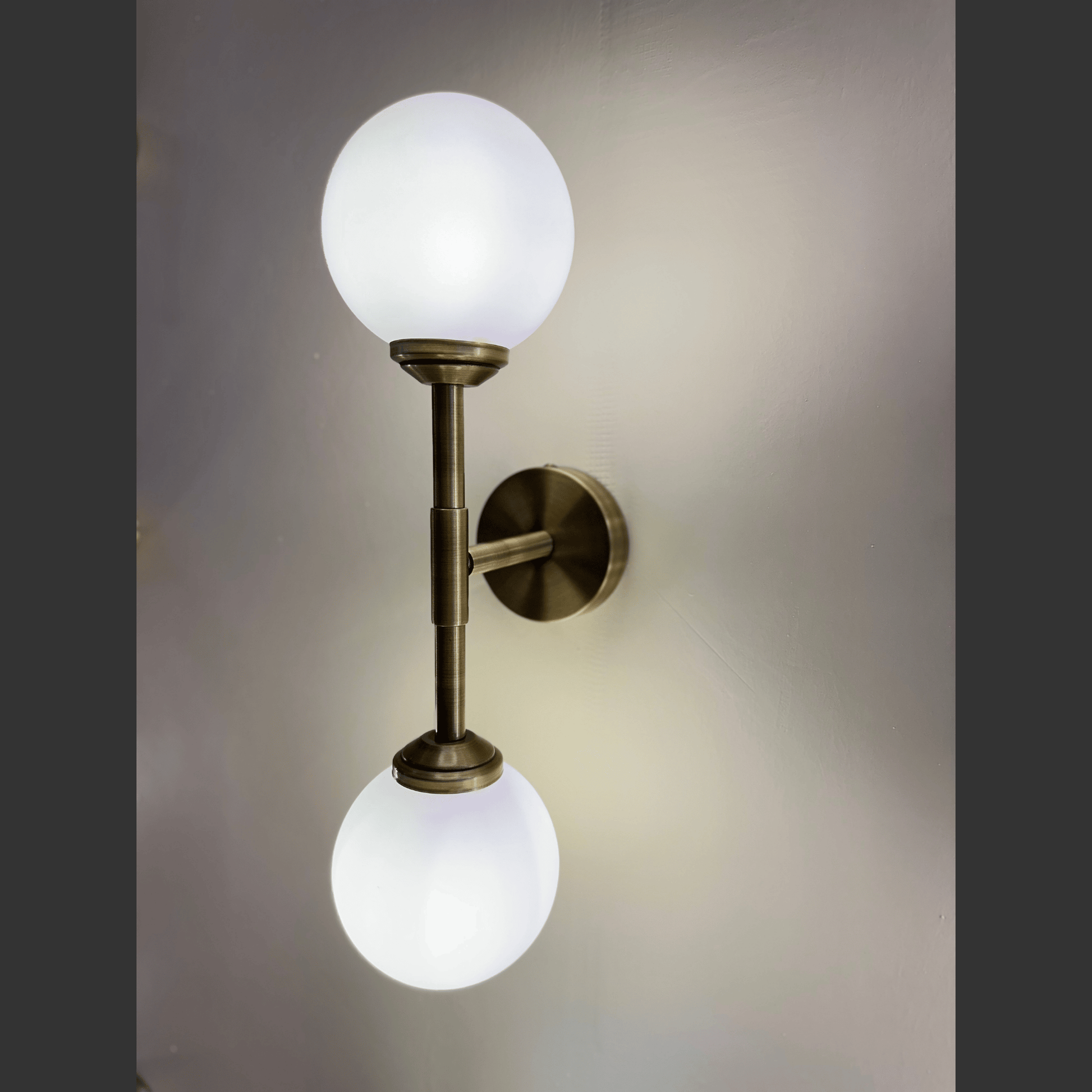 Wall-mounted lamp with two white globe lights on a gray background