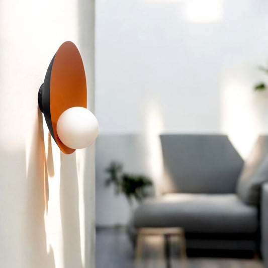 Wall-mounted sconce with burnt orange interior and opal globe bulb in a modern living space with natural light